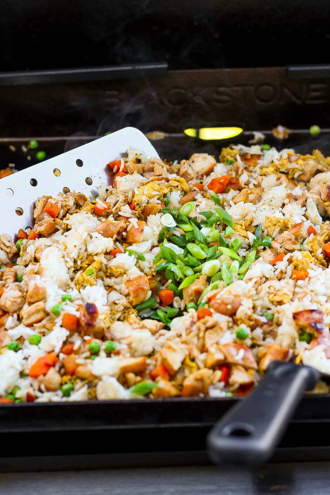 Two spatulas moving fried rice around on a Blackstone griddle.