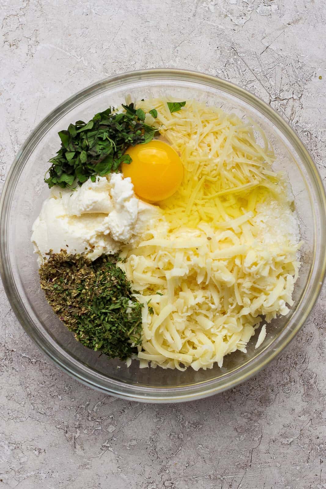 The ingredients for the ricotta mixture separated in a glass bowl.