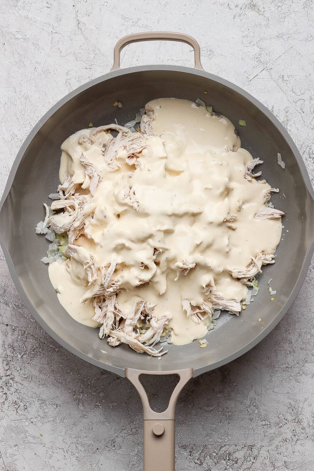 Shredded chicken and alfredo sauce in a large skillet.