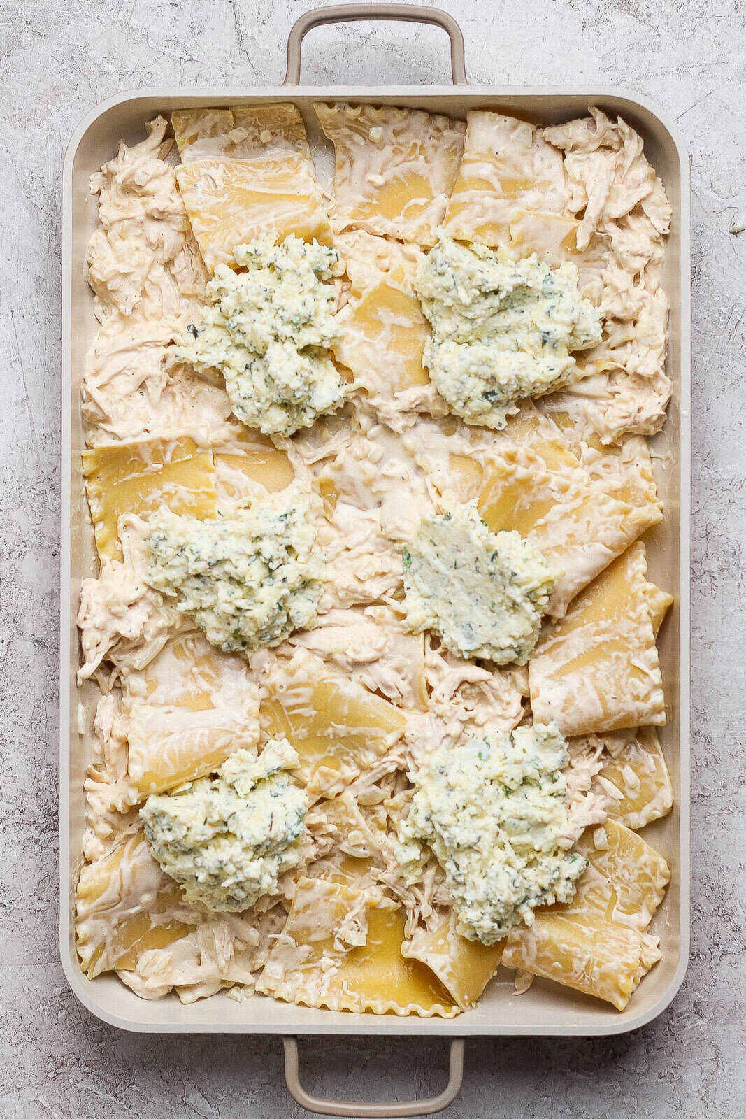 Dollops of the ricotta mixture added to the top of a chicken alfredo sheet pan lasagna.