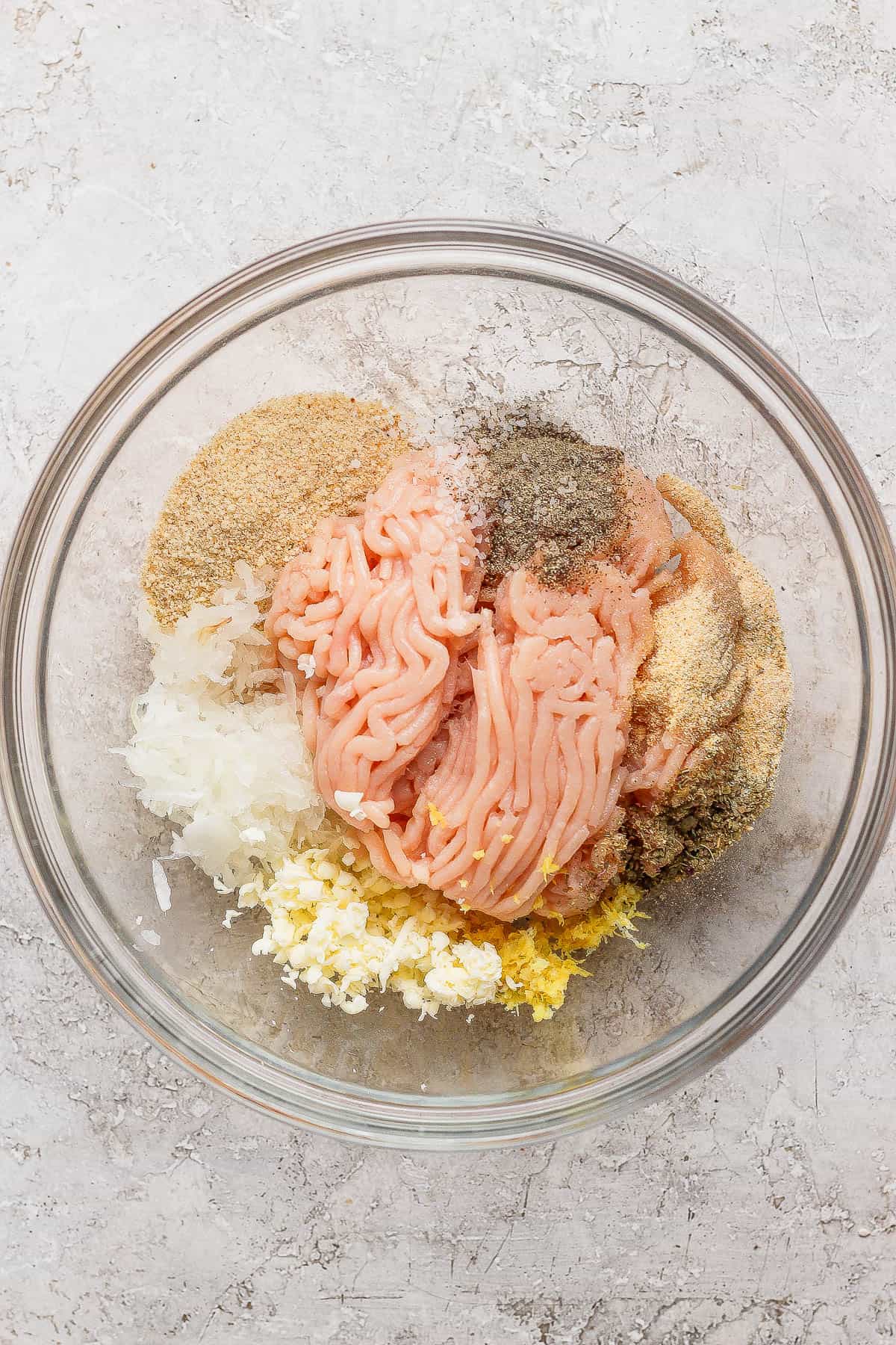 Meatball ingredients in a large, glass bowl.