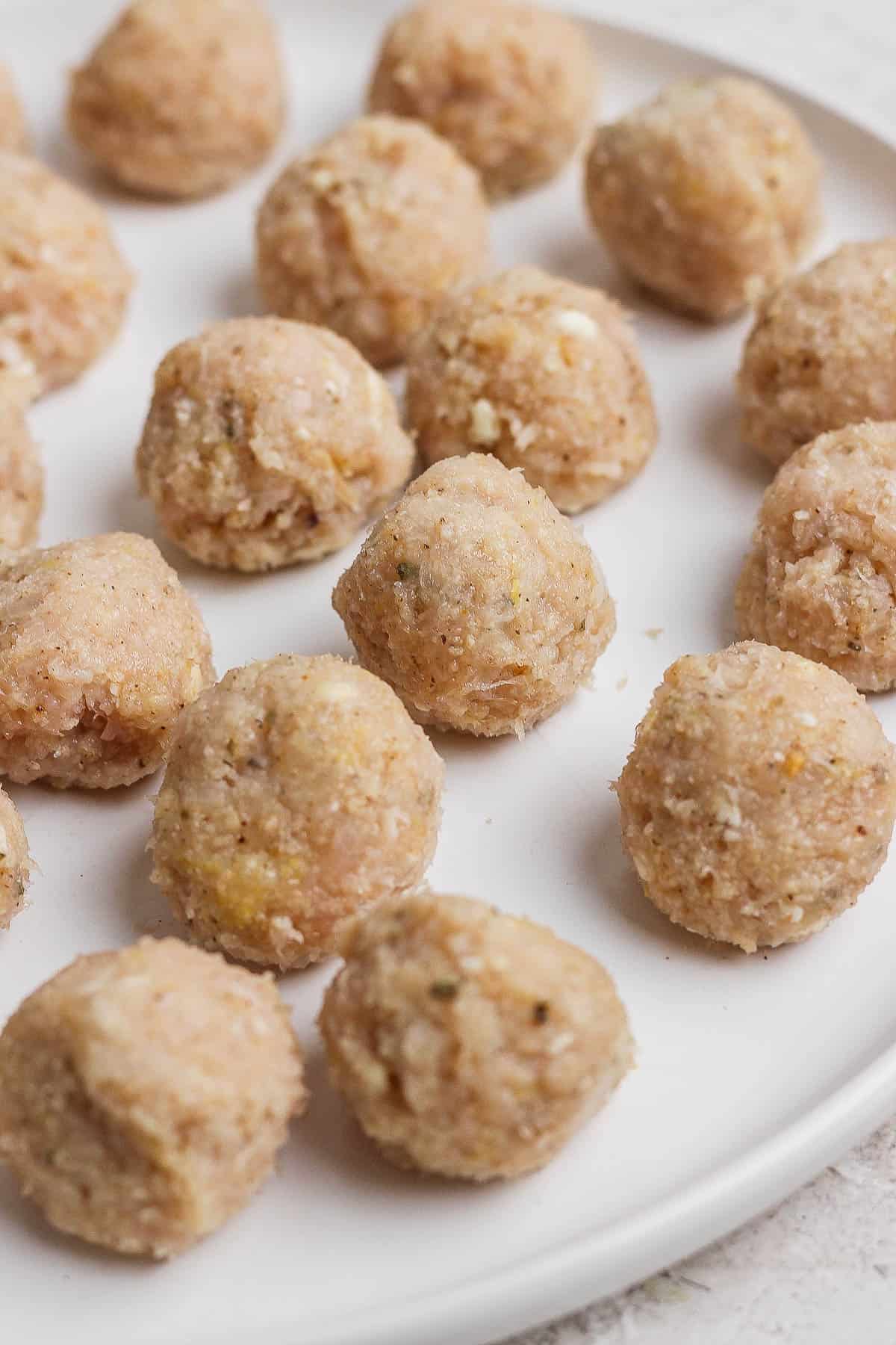 Formed chicken meatballs on a white plate.