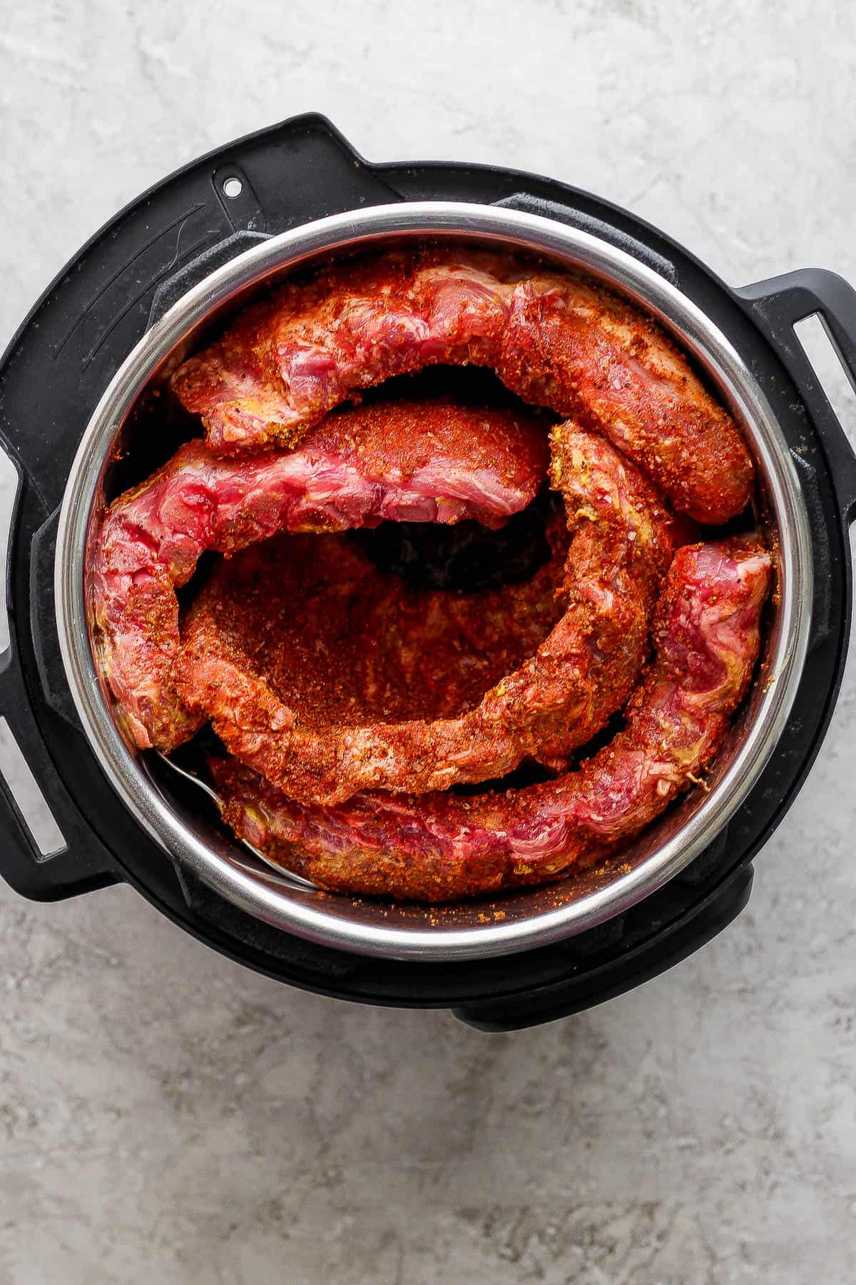 Seasoned racks of ribs placed in an Instant Pot before cooking.