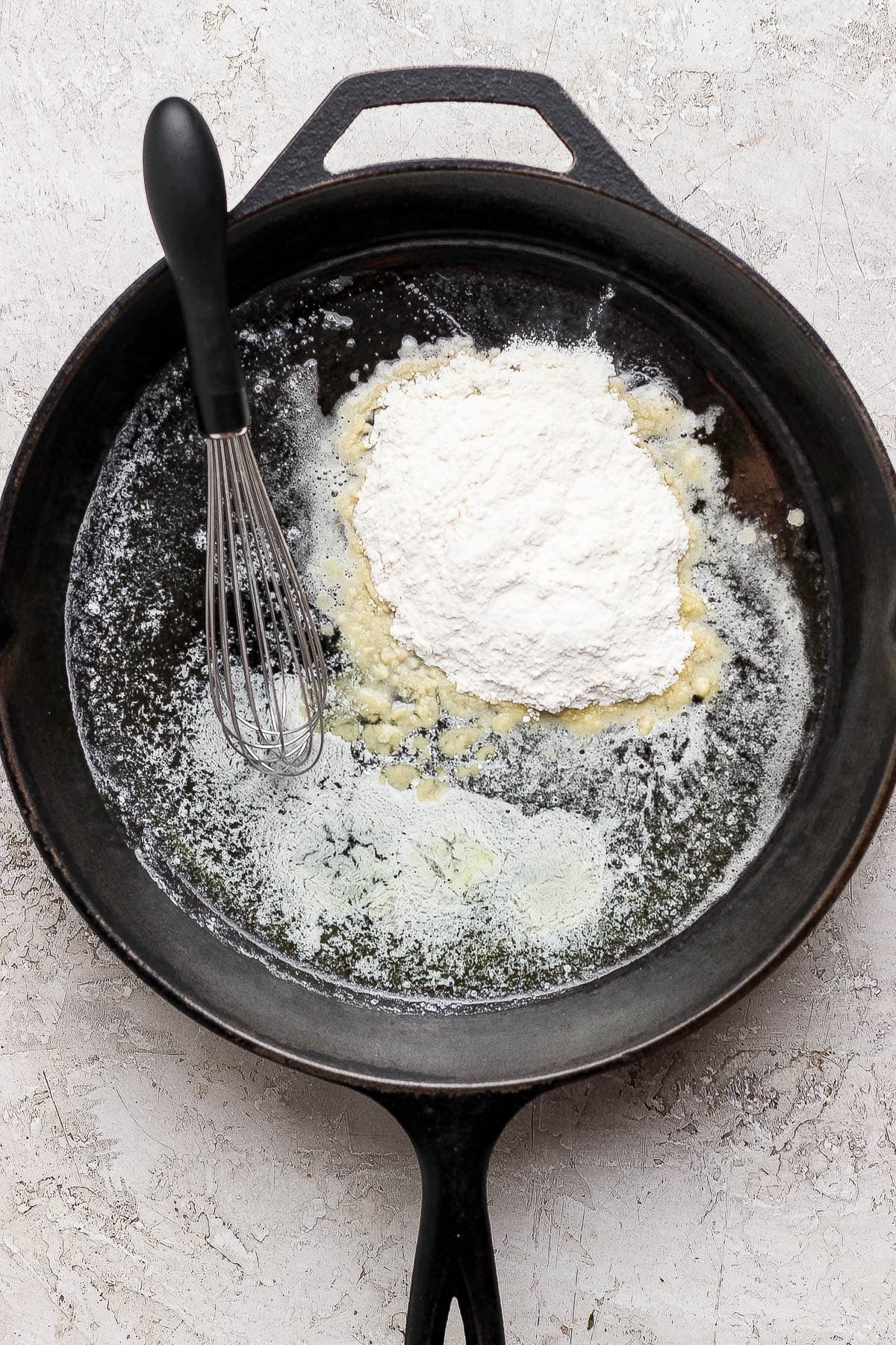 Melted butter in a large skillet with flour and a whisk.