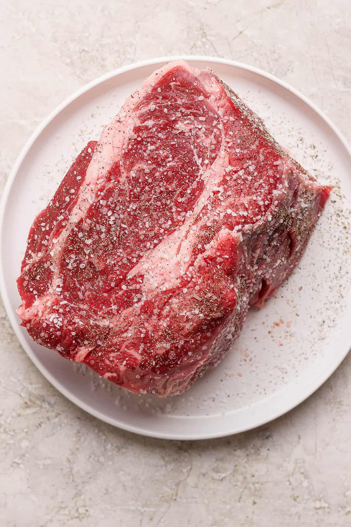 A seasoned chuck roast on a white plate.