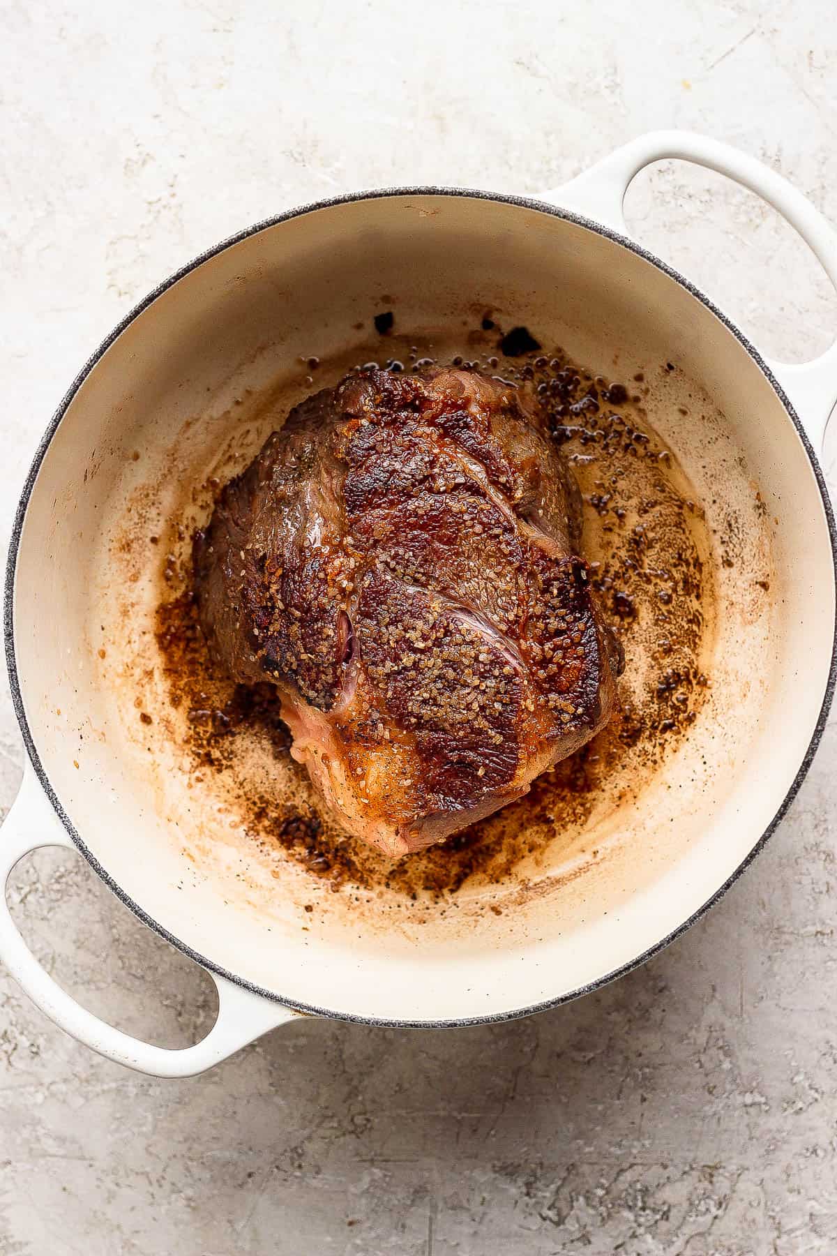 The chuck roast searing in a large dutch oven.