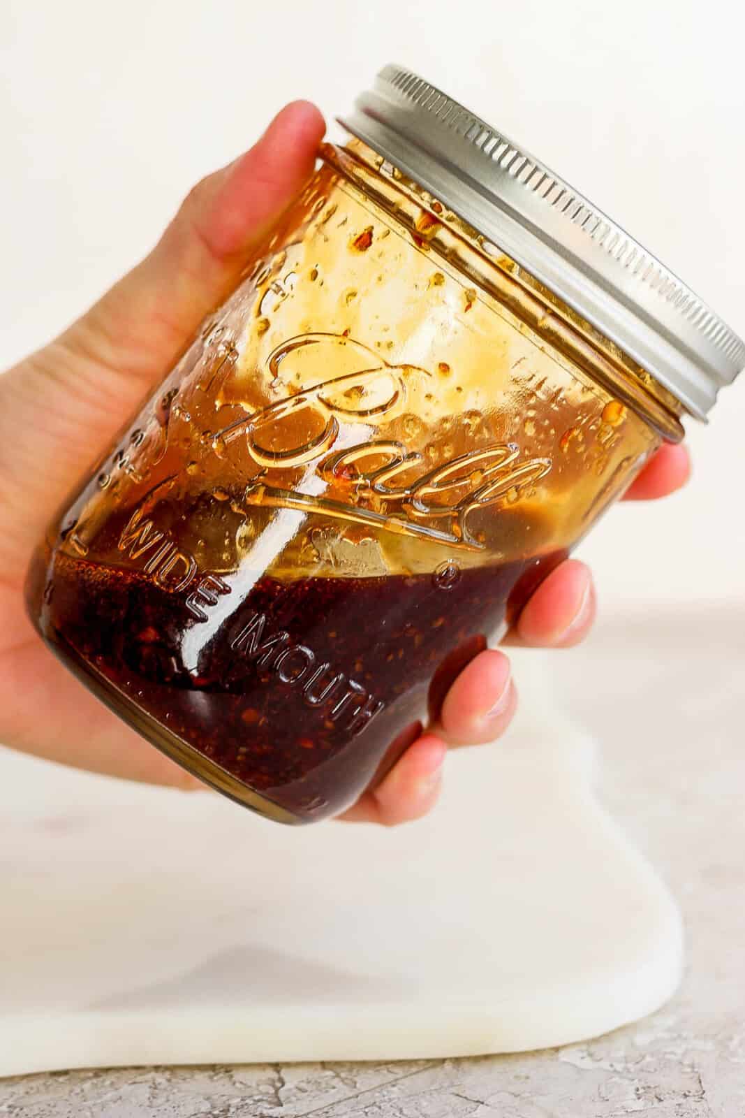 A hand holding a jar of fried rice sauce before adding it to Blackstone shrimp fried rice.