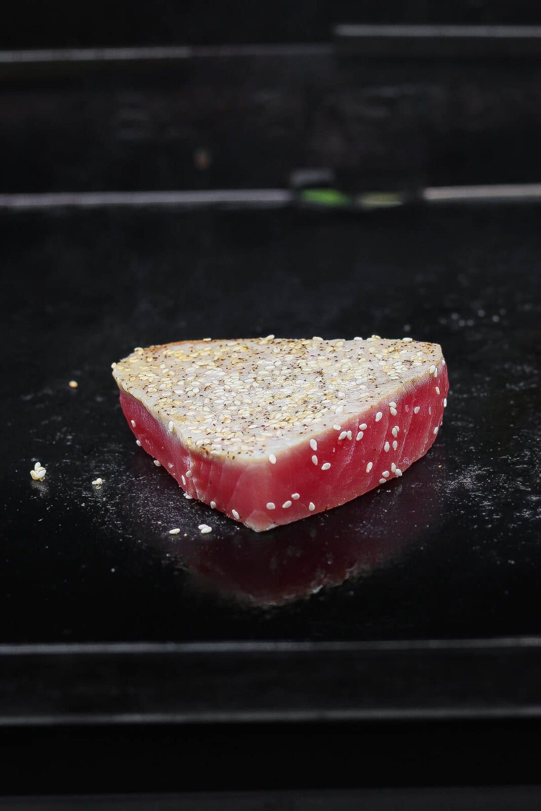 A tuna steak being cooked on a flattop griddle.