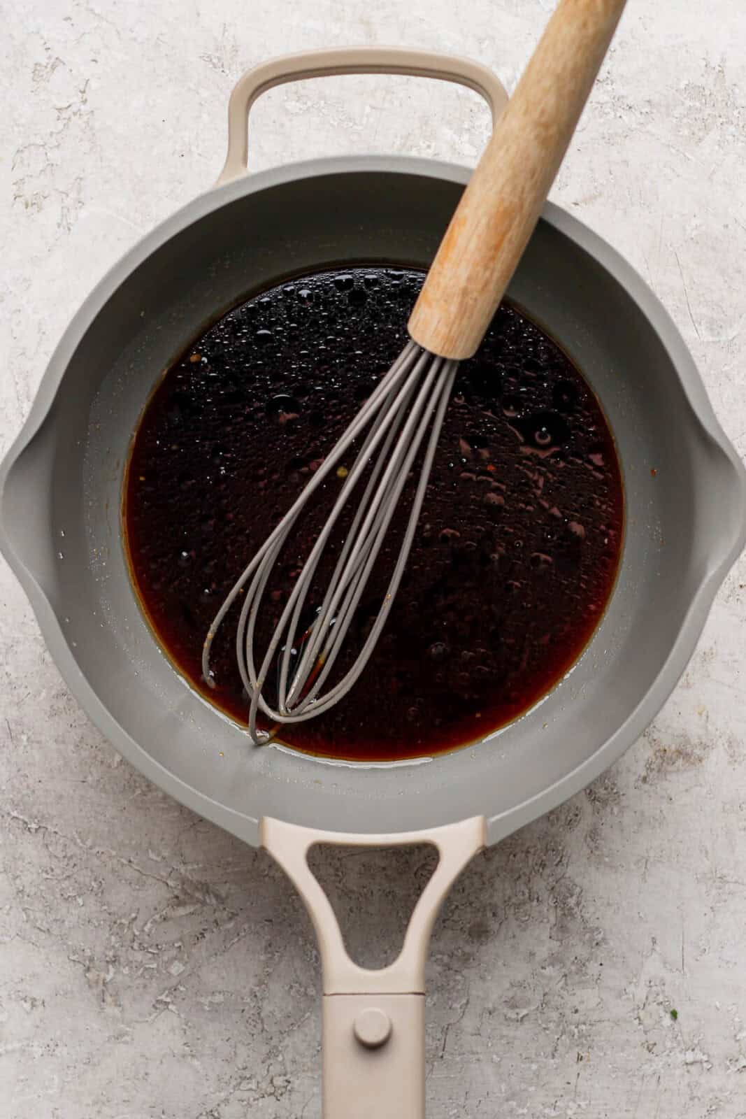 A tuna steak dipping sauce in a saucepan with a whisk.