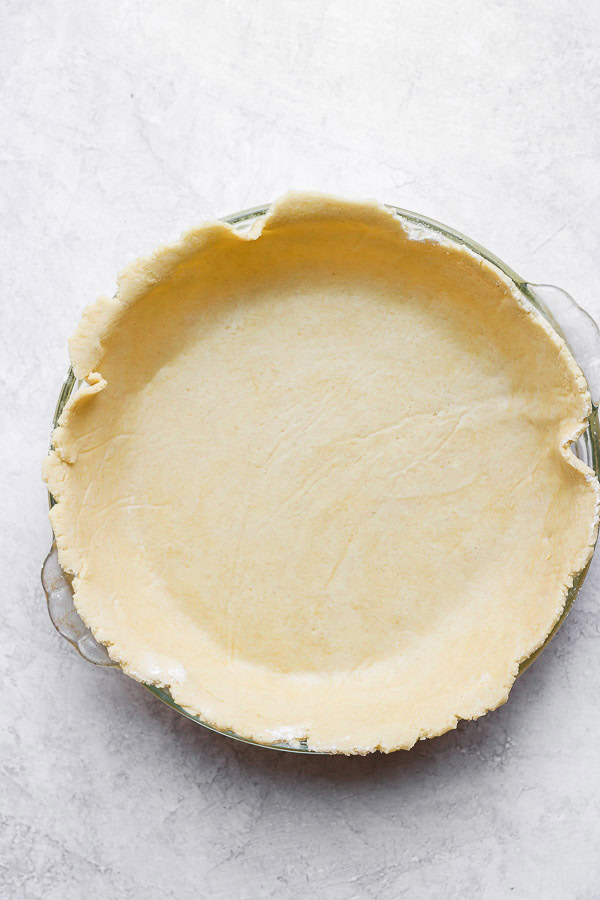 A gluten free pie crust in a glass pie pan before baking.