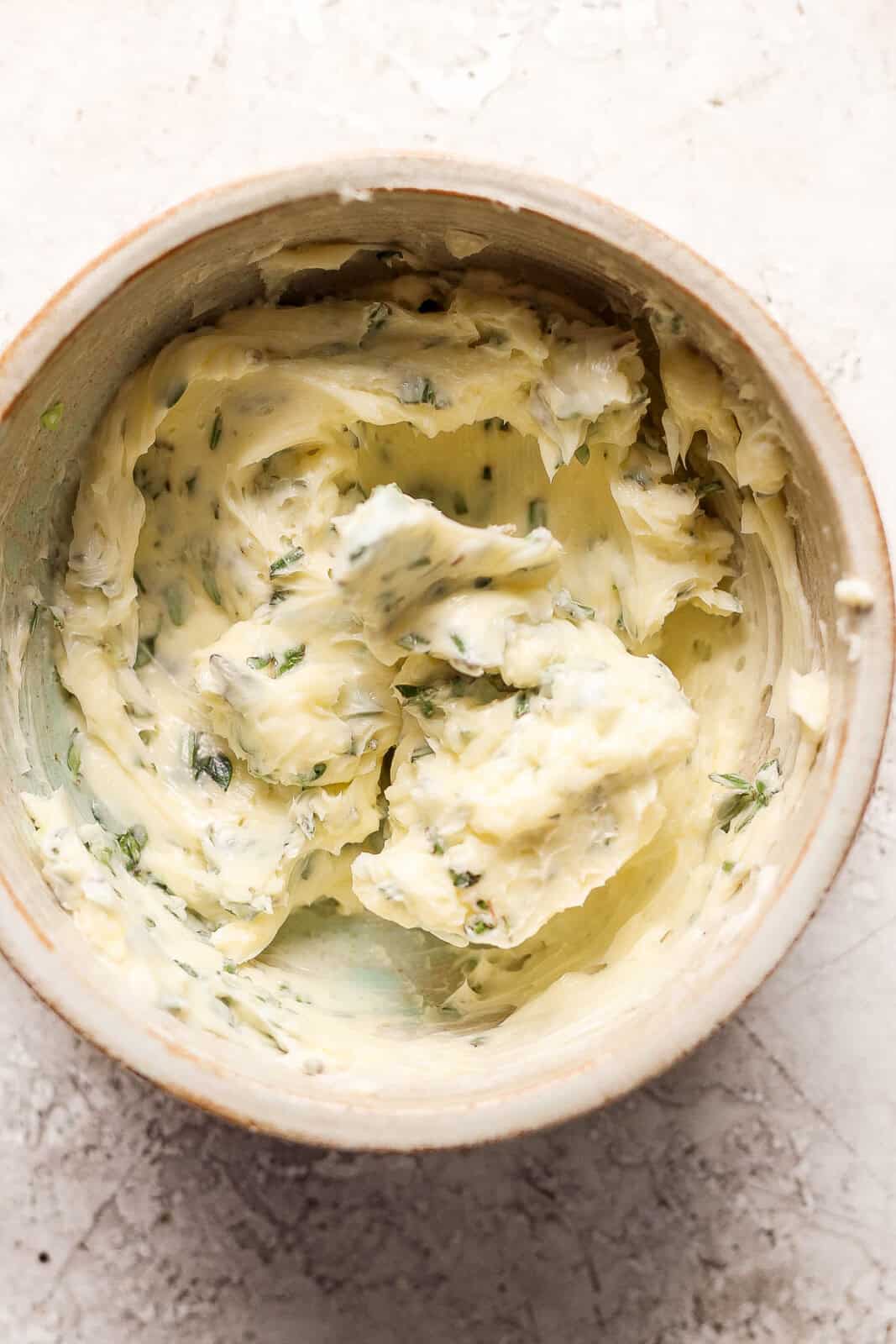 Soft butter and fresh herbs mixed in a small bowl.
