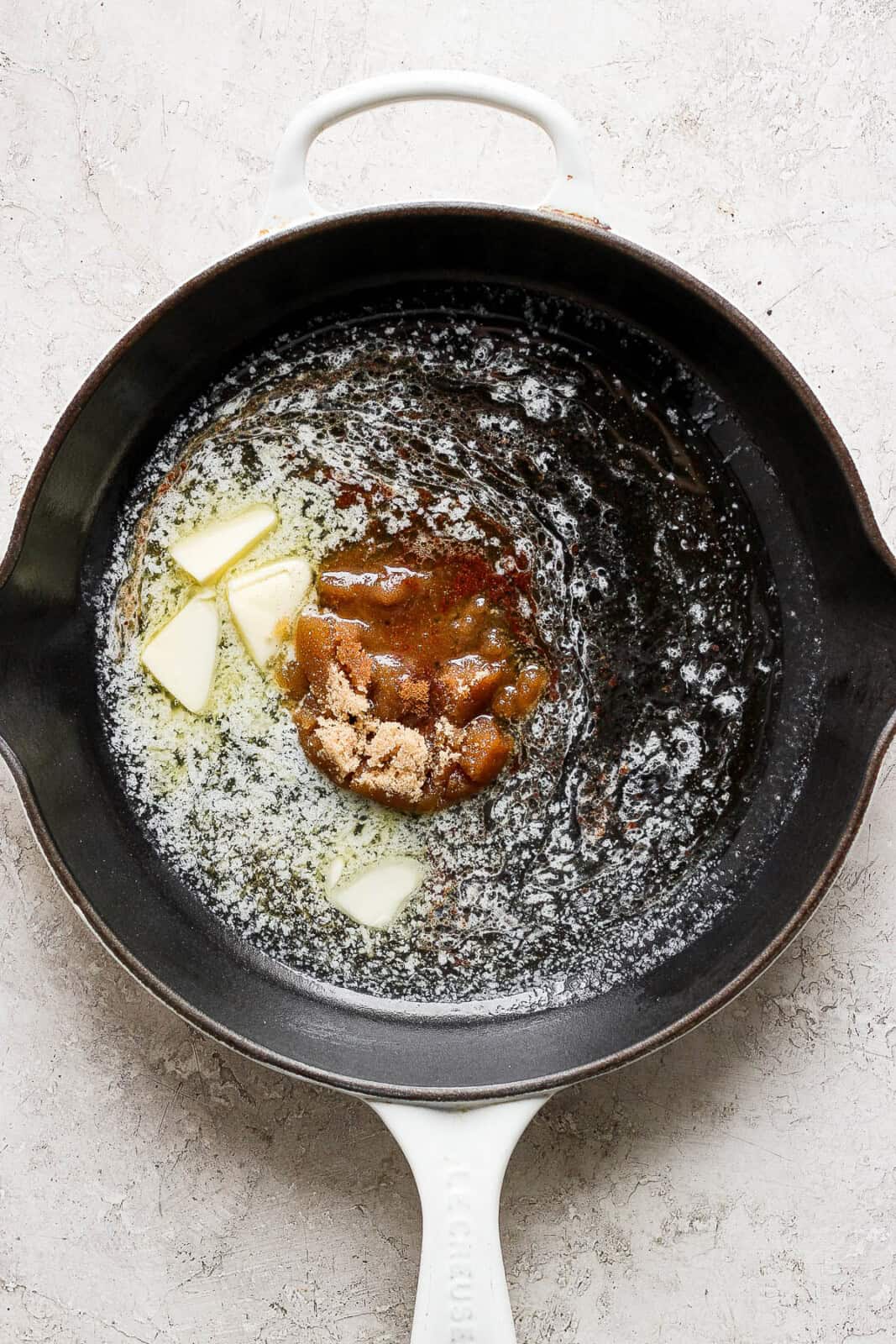 Brown sugar, butter, bourbon, cinnamon, and salt added to a cast iron skillet.