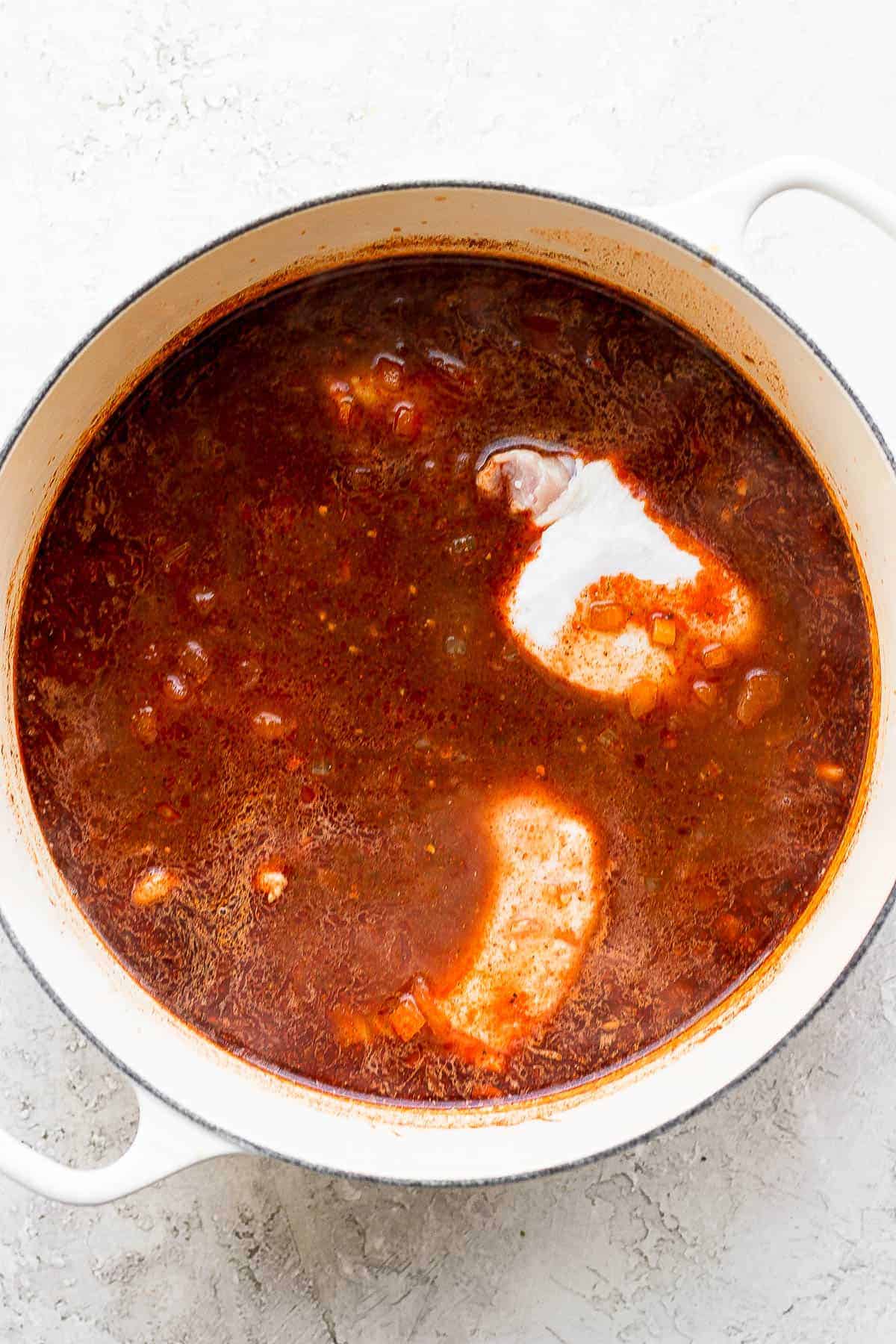 Chicken breasts cooking in a pot of chicken enchilada soup.
