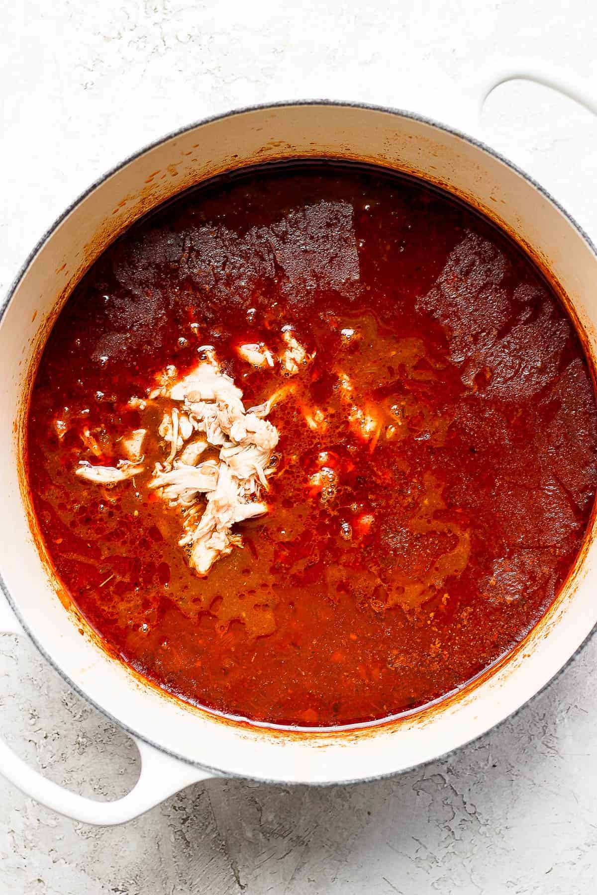 Shredded chicken returned to a pot of chicken enchilada soup.