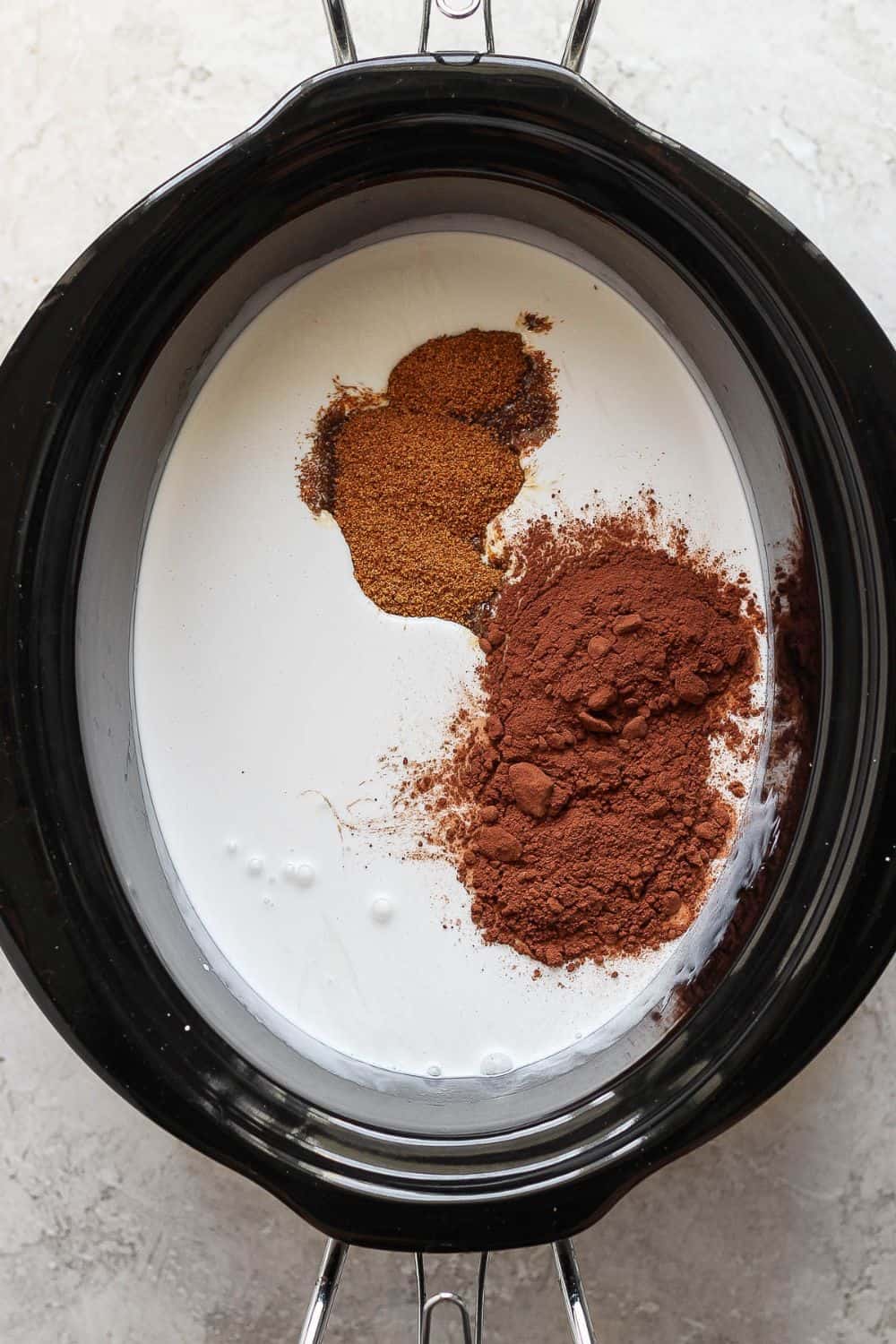 Whole milk, heavy whipping cream, sugar, vanilla, and cocoa powder added to a crock pot.