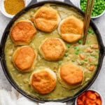 A chicken curry pot pie in a skillet with biscuits and two spoons sticking out, fully cooked.