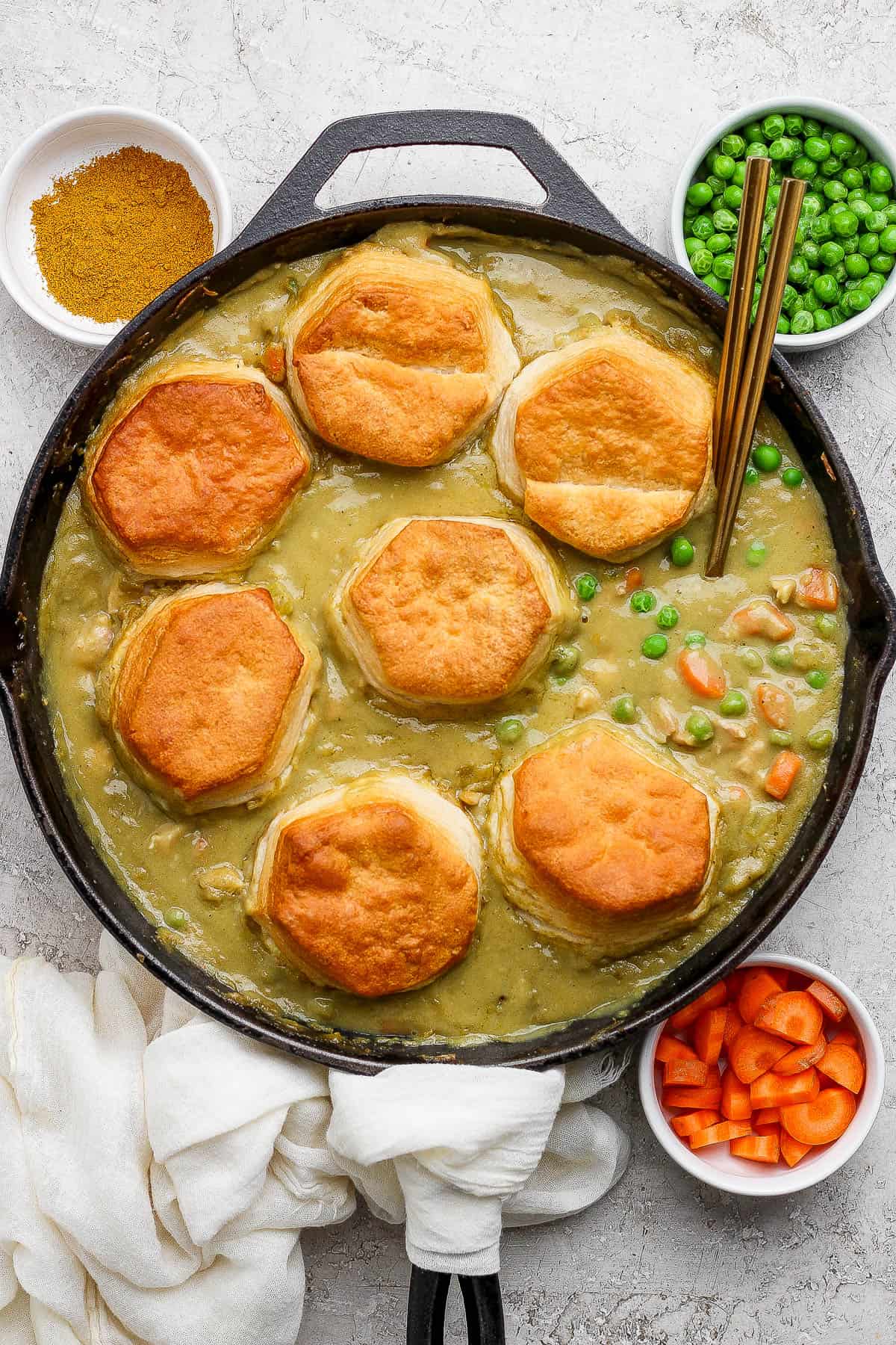 Baked curry chicken pot pie in a skillet with baked biscuits on top.