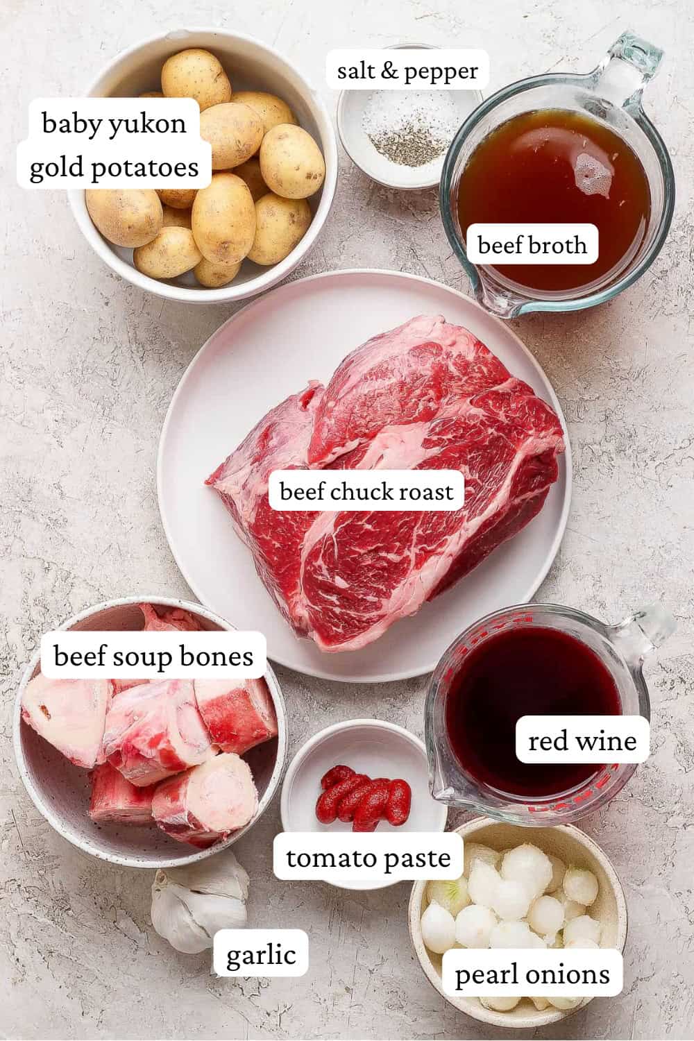 Dutch oven pot roast ingredients in separate bowls and a chuck roast on a plate.