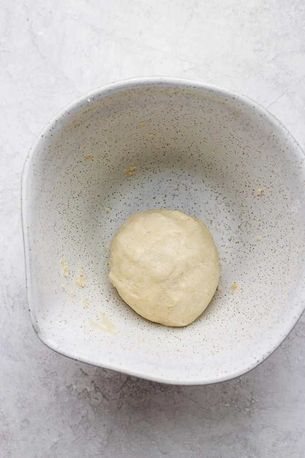A ball of gluten free pie dough in a mixing bowl.