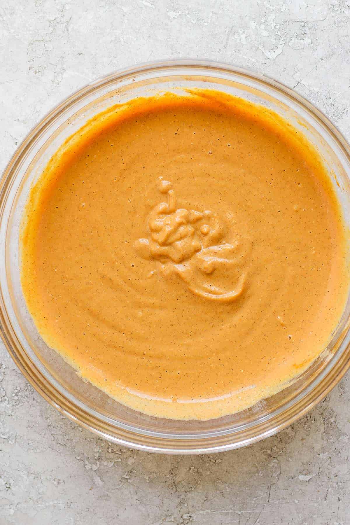 Pumpkin pie filling fully whisked together in a glass bowl.