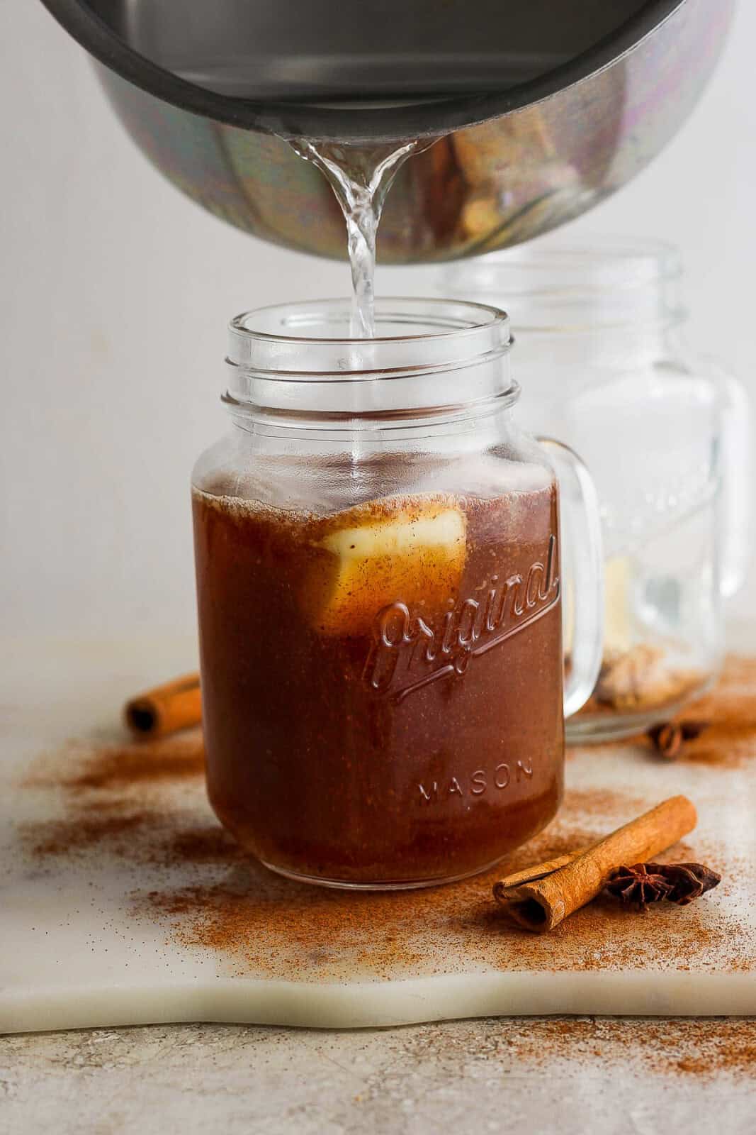 In a large mug, add 1 tablespoon butter, brown sugar, cinnamon, cloves, nutmeg, vanilla extract, and rum in a glass mug. Water pouring over the top.