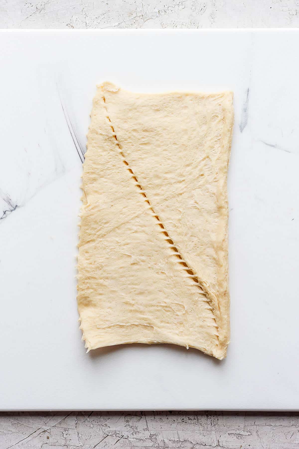 A section of crescent roll dough on a marble board.