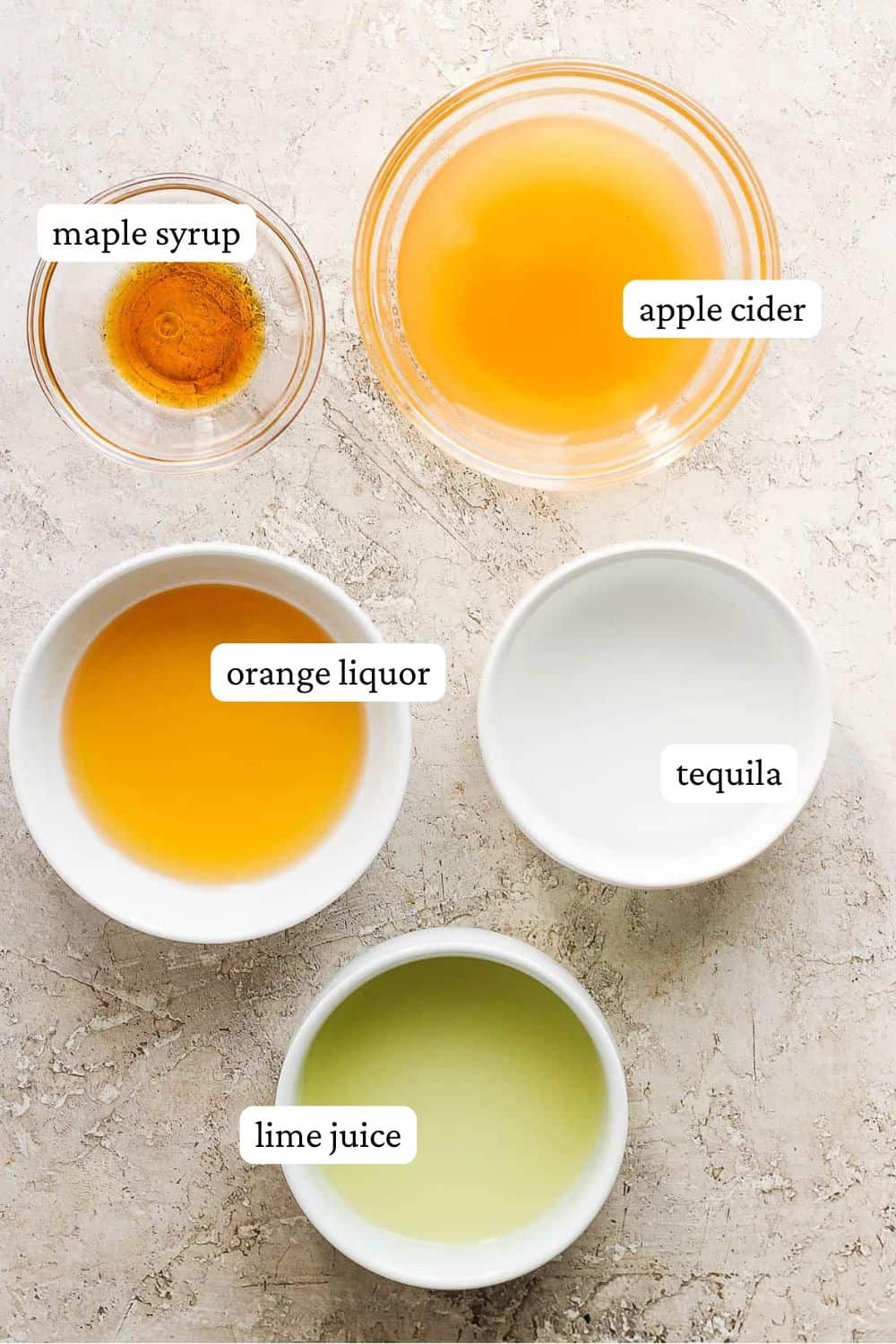 Small bowls filled with the ingredients for apple cider margaritas and labeled.