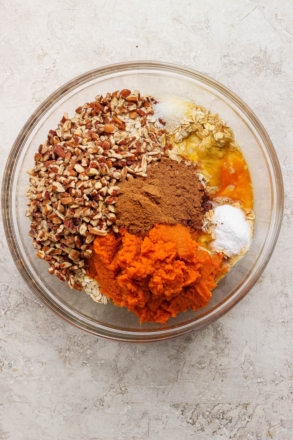 Pumpkin baked oatmeal ingredients in a large, glass bowl.