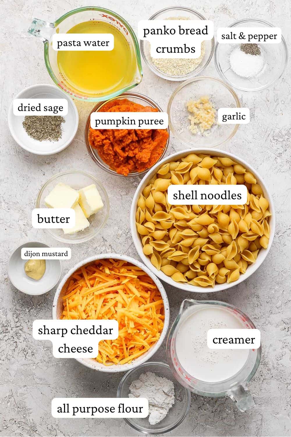 Individual bowls of pasta water, panko bread crumbs, salt & pepper, dried sage, pumpkin puree, minced garlic, butter, shell noodles, dijon mustard, shredded sharp cheddar cheese, creamer, and all-purpose flour.