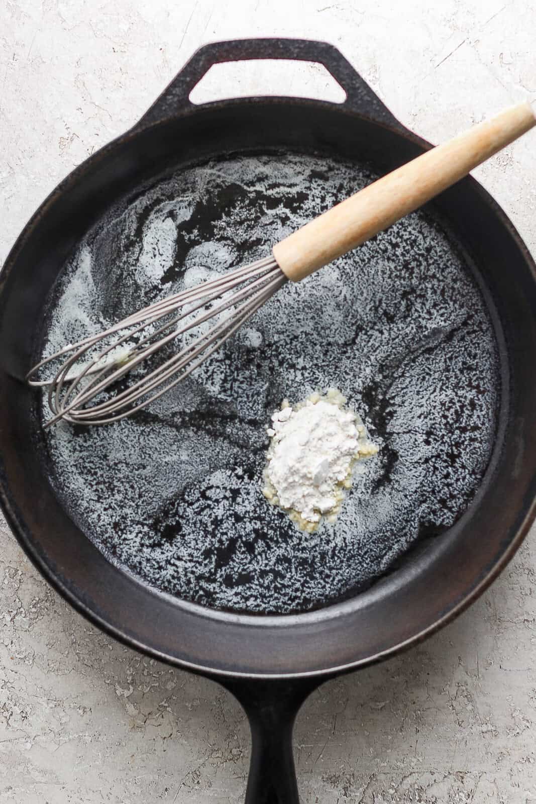 Melted butter in a cast iron skillet with flour being whisked in.