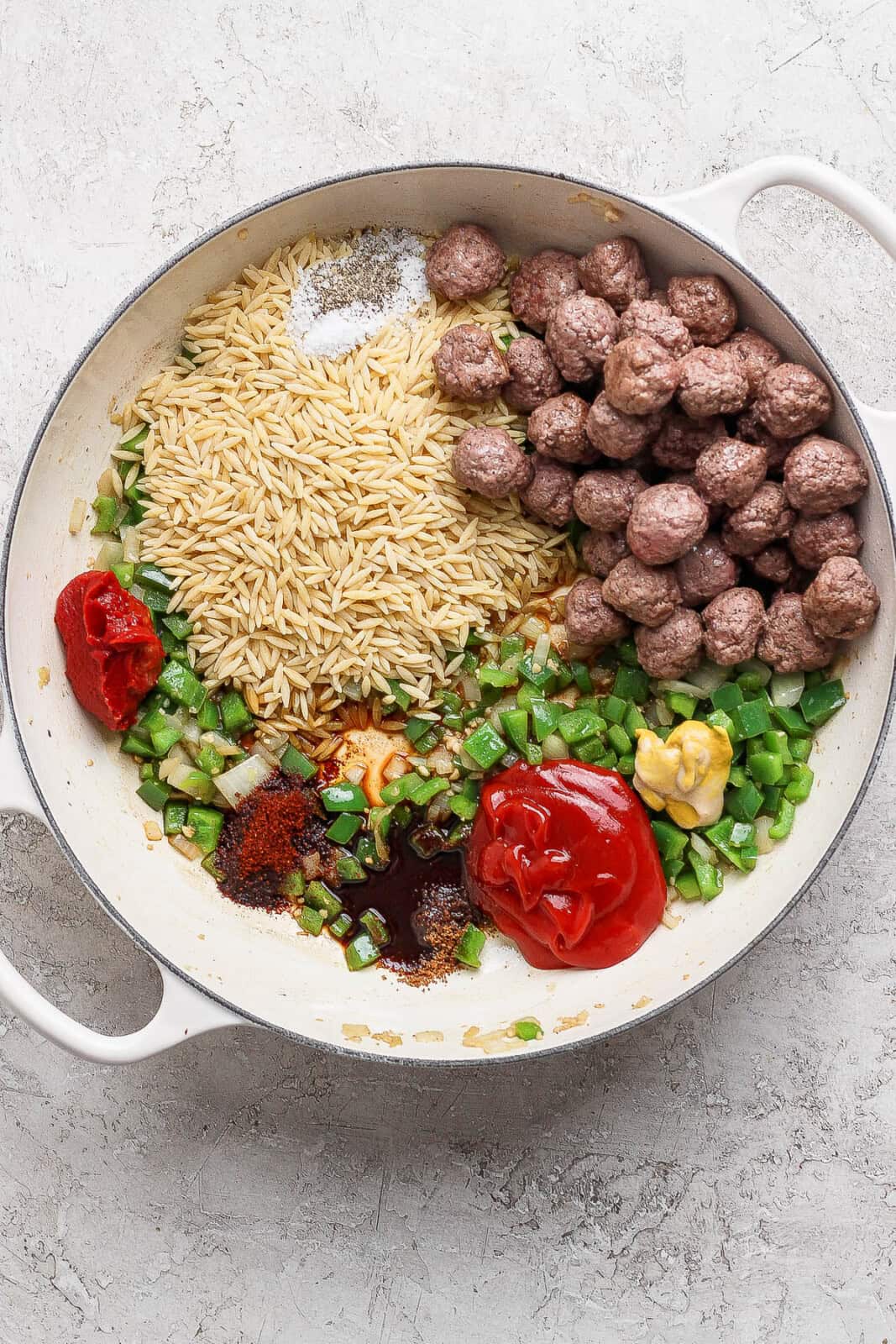 All of the sloppy joe orzo ingredients in a braising pan, except the cheese and broth.