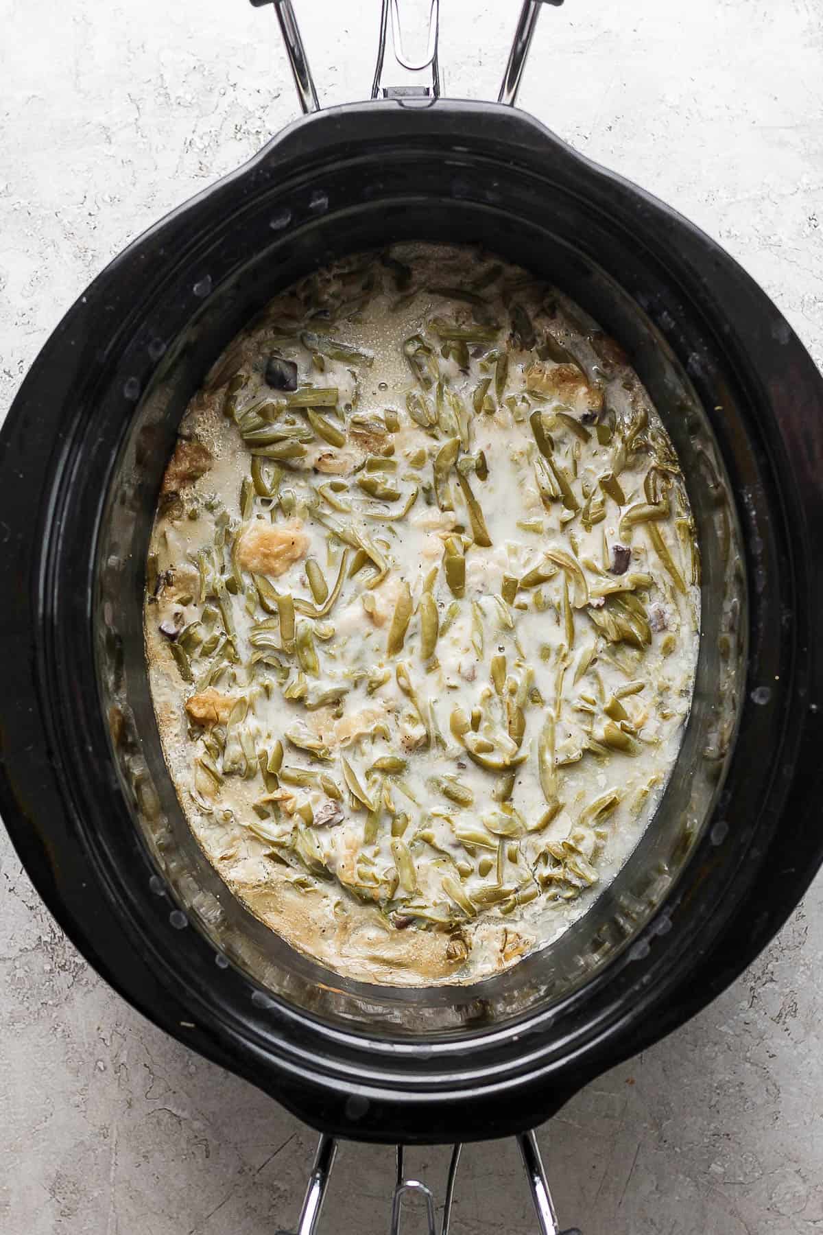 Crock pot green bean casserole fully mixed in the slow cooker before cooking.