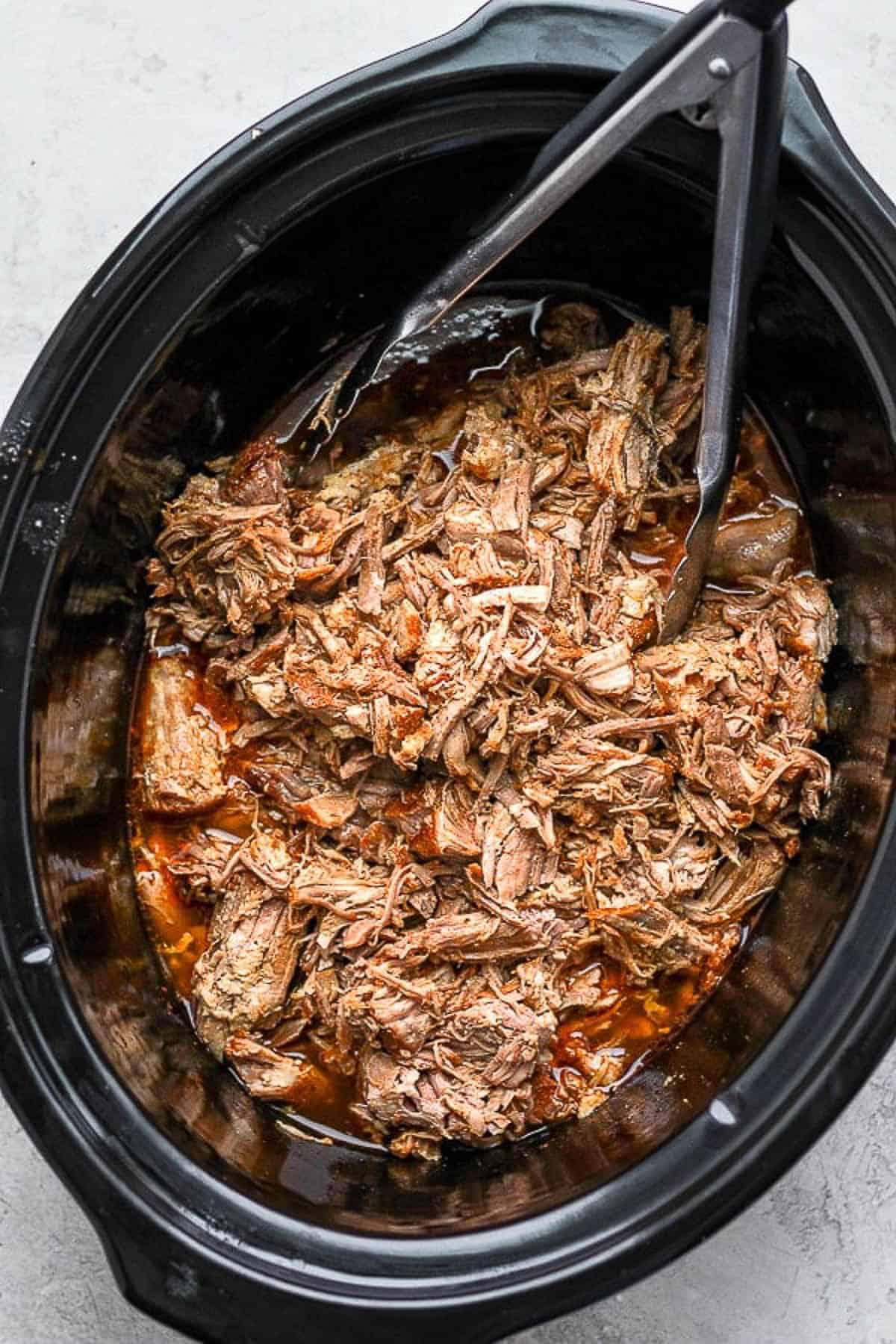 Shredded slow cooker pulled pork returned to the slow cooker and tossed in the juices with tongs.