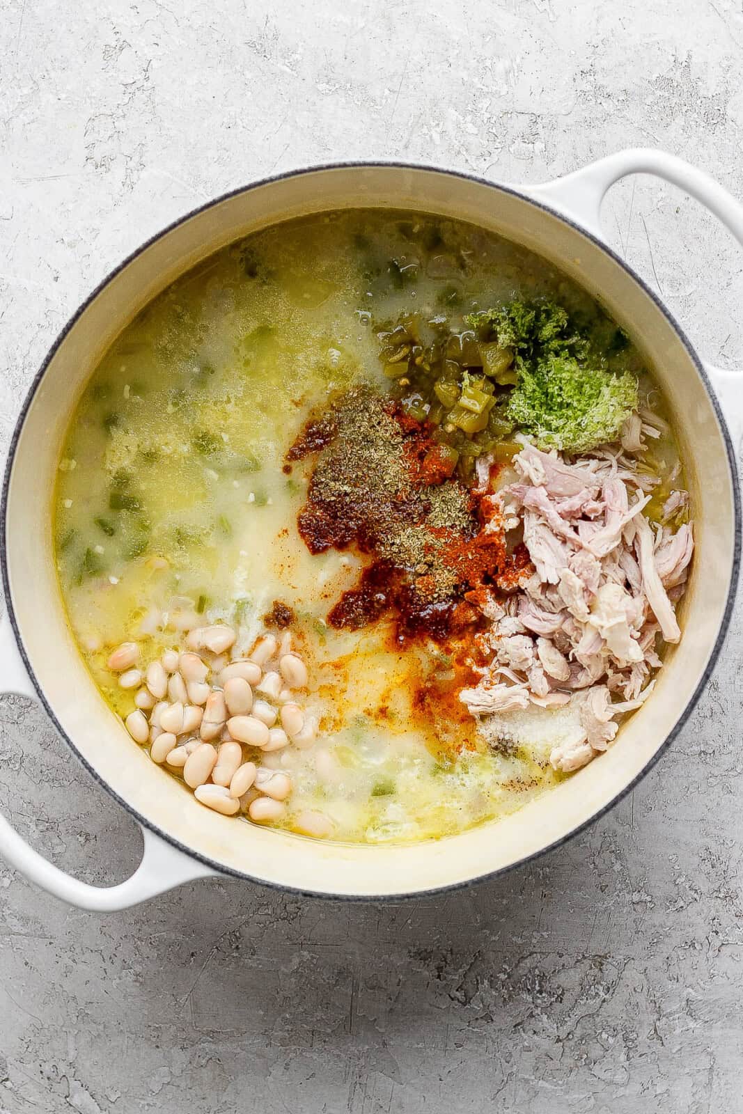 A dutch oven full of the ingredients for a Mexican street corn white chicken chili (except for cream cheese and street corn mixture) before mixing.