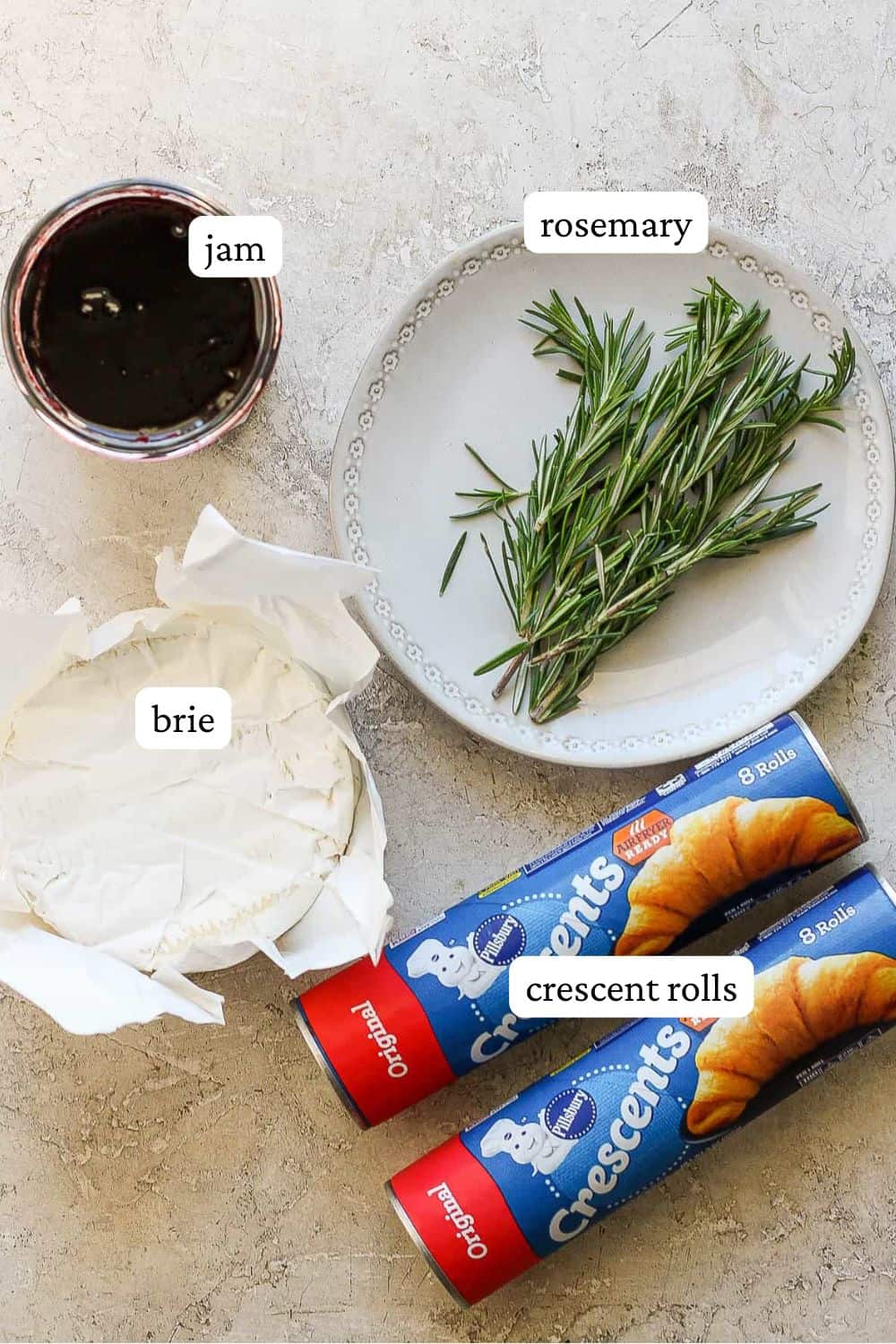 Baked brie bites ingredients including jam, fresh rosemary, brie cheese, and refrigerated crescent rolls.