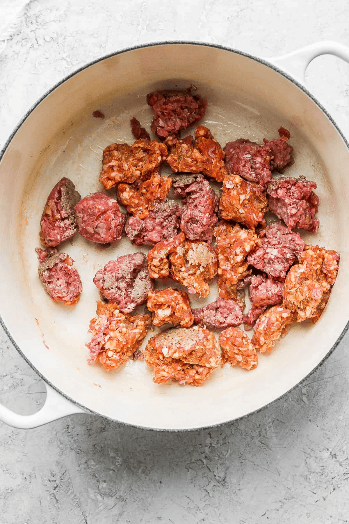 Ground beef and Italian sausage broken apart in a dutch oven.