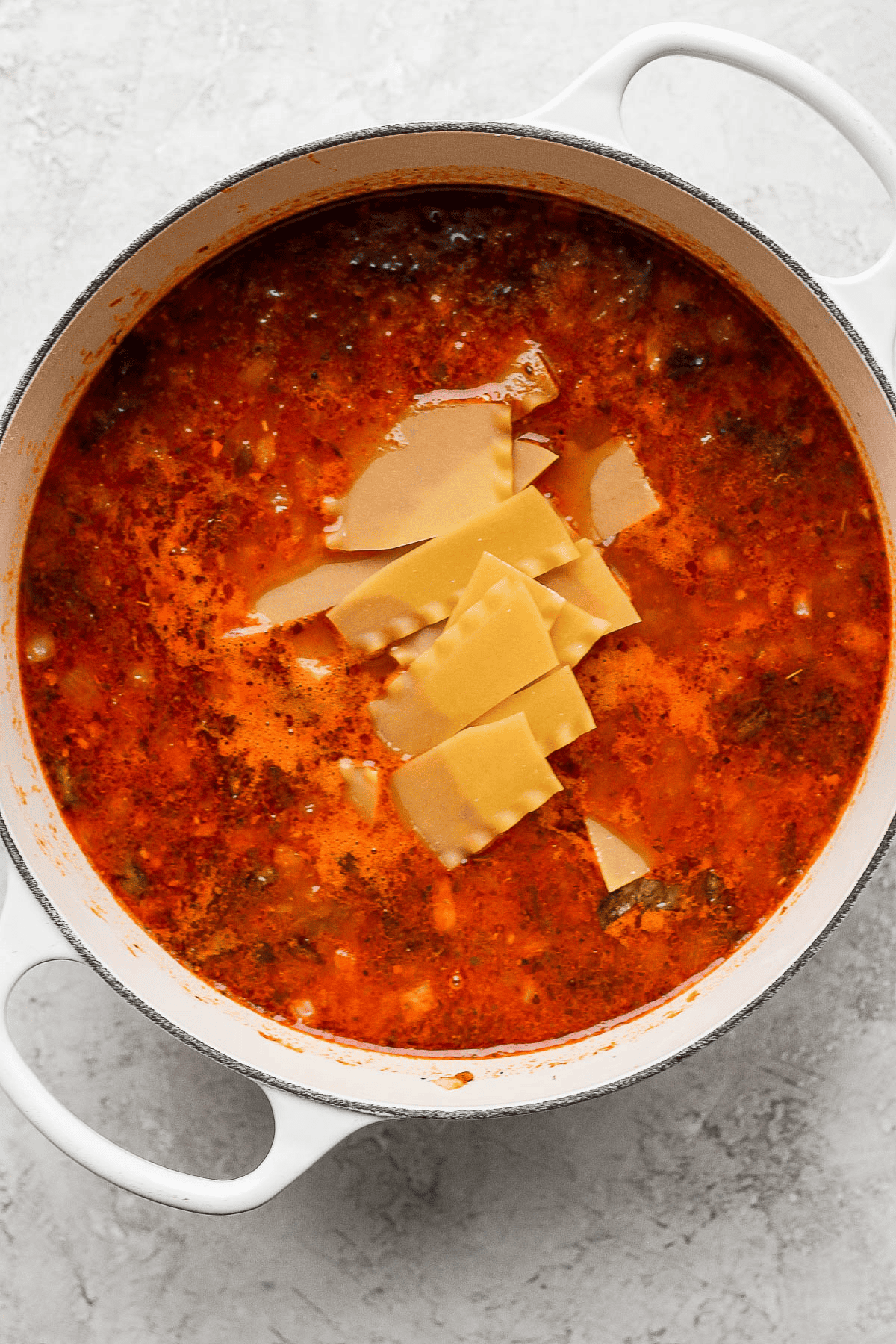 Broken lasagna noodles added to a pot of lasagna soup.
