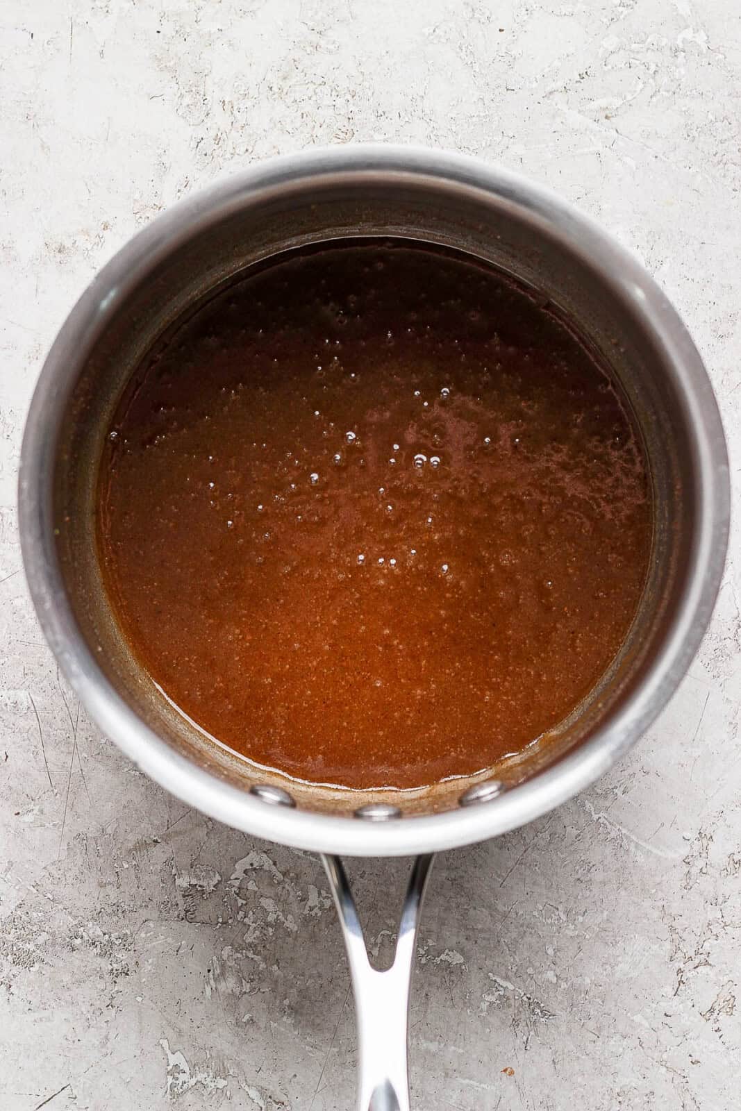 Brown sugar, white sugar, vanilla, butter, nutmeg, and lemon zest, and cinnamon, and bourbon in a sauce pan combined into a sauce.