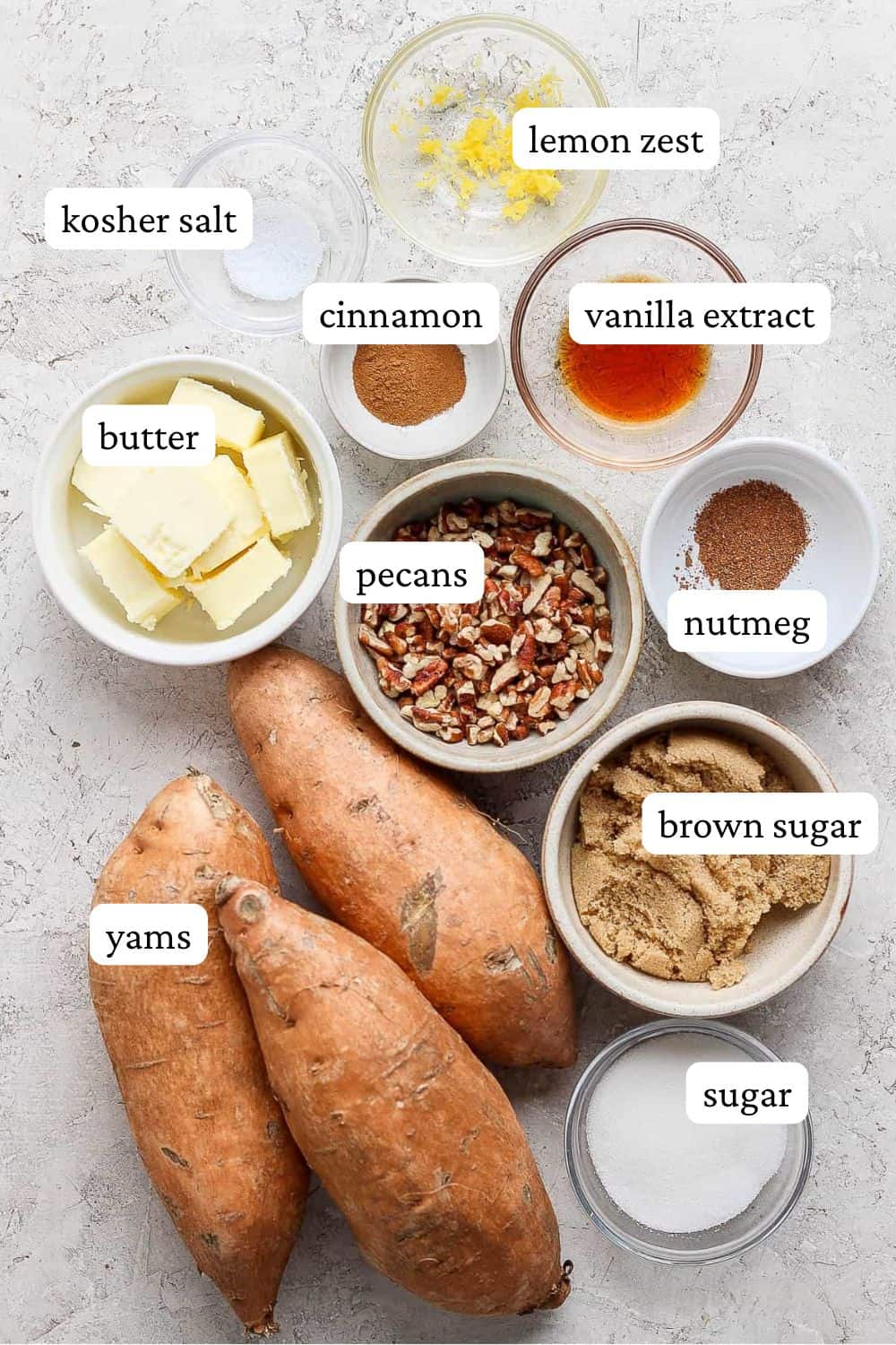 Candied yams ingredients; Individual bowls of salt, lemon zest, cinnamon, vanilla extract, butter, pecans, nutmeg, brown sugar, white sugar, and three whole yams.