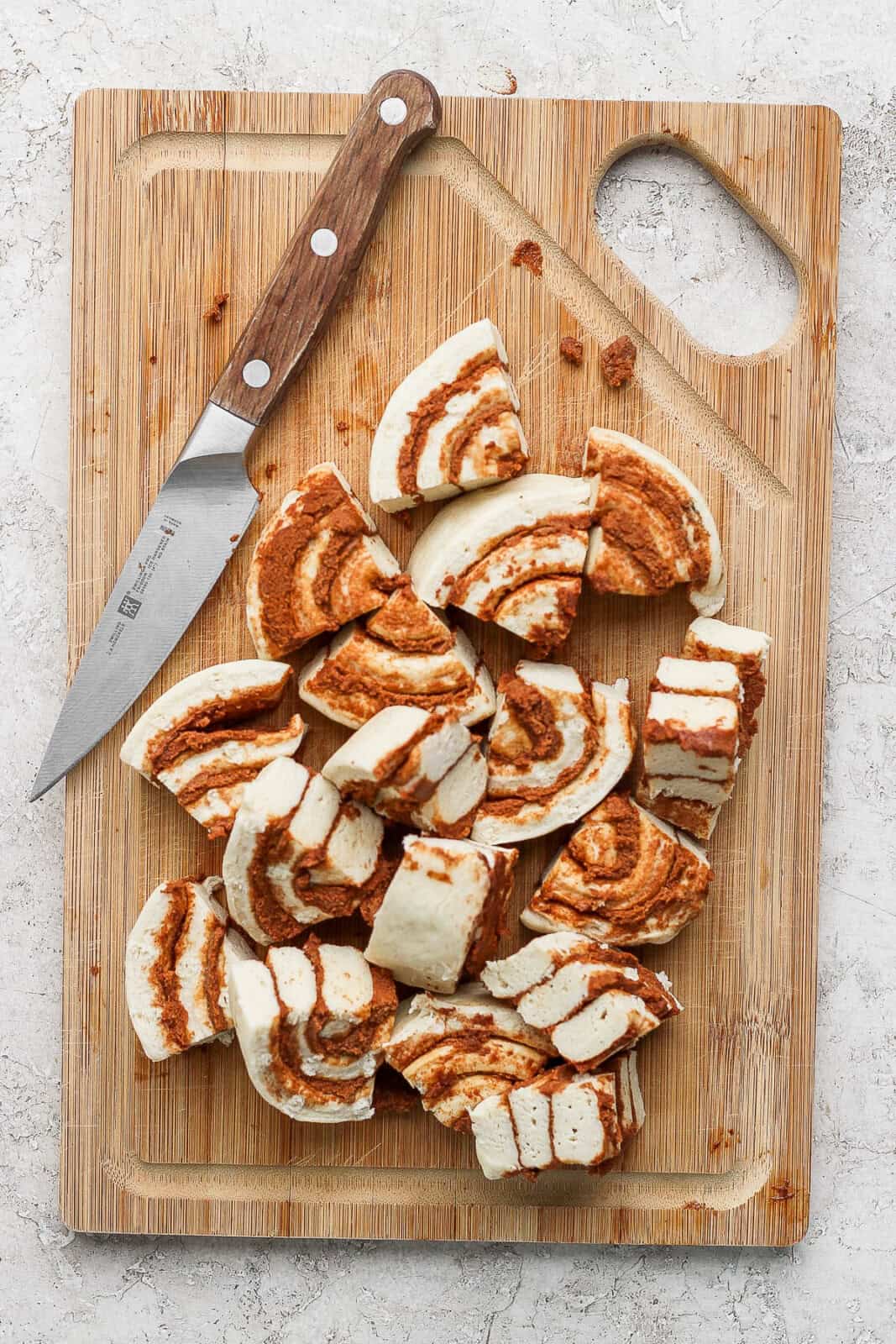 Cinnamon rolls quartered on a cutting board to make cinnamon roll casserole.