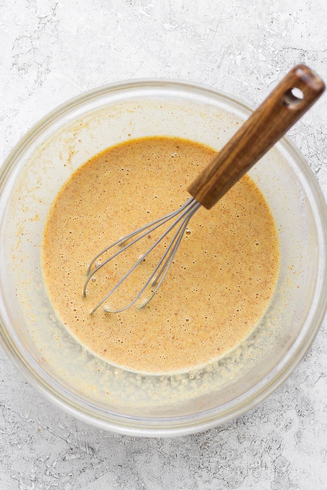 Eggs, vanilla, creamer, cinnamon and nutmeg whisked together in a bowl to make the binder for cinnamon roll casserole.