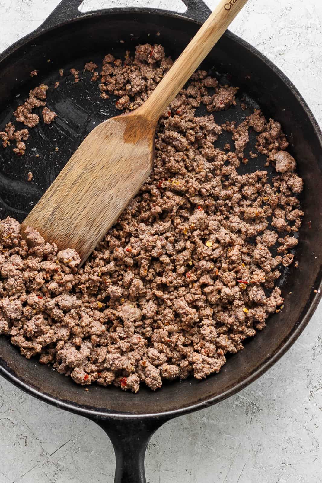 Ground beef cooking in a cast iron skillet.