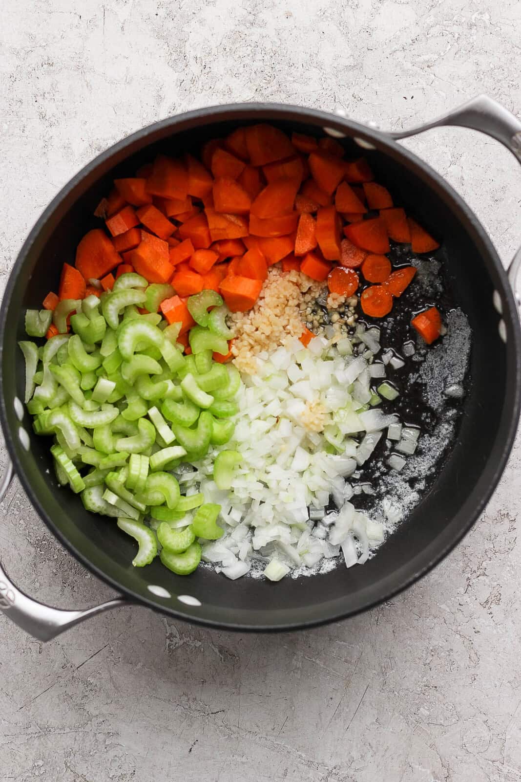 Carrots, celery, onion, garlic, and butter added to large stock pot to make creamy ham and potato soup.