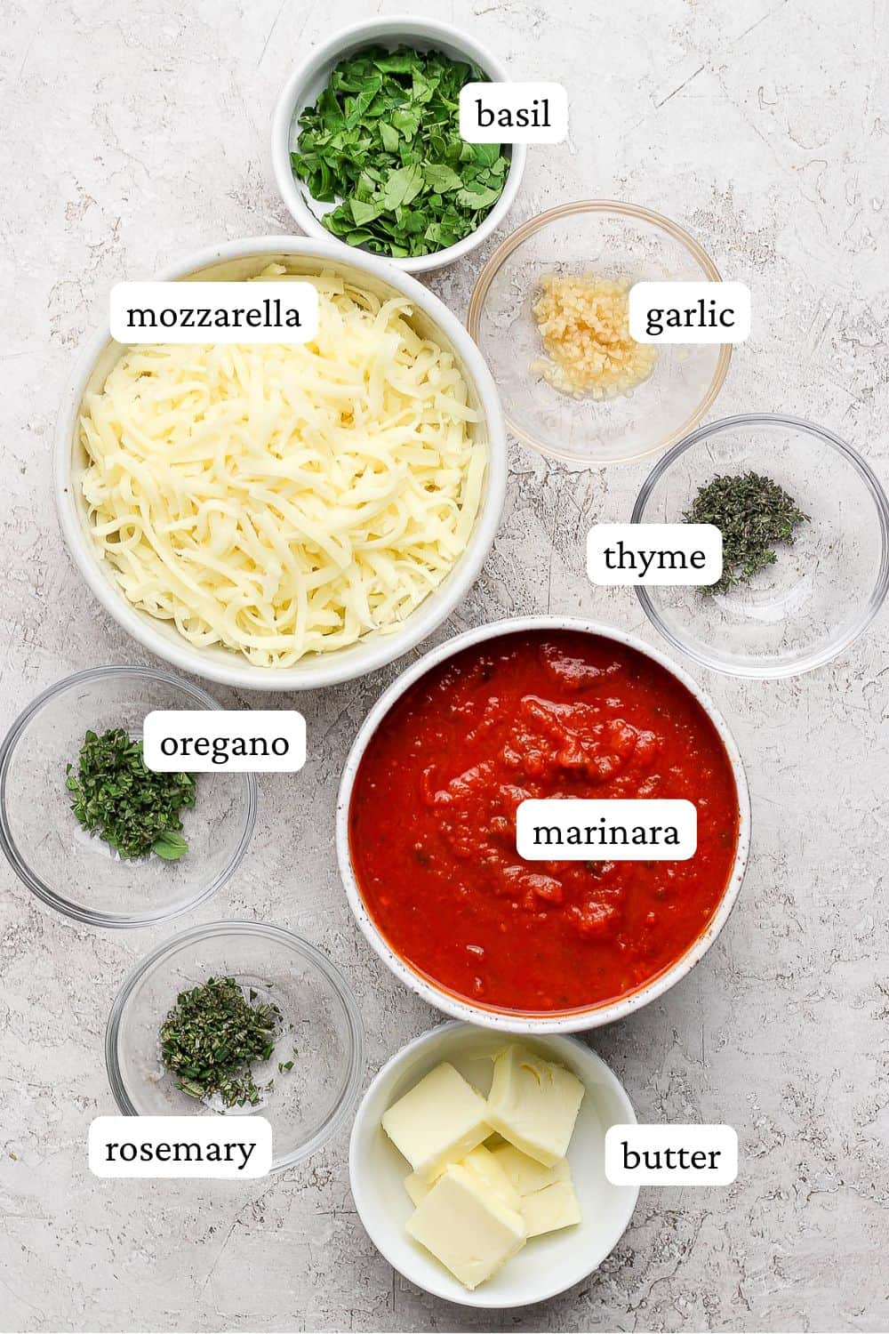 Italian dunkers ingredients including shredded mozzarella cheese, marinara sauce, garlic, fresh basil, oregano, thyme, rosemary, and butter.