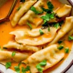 A bowl of potsticker soup with fresh parsley on top.
