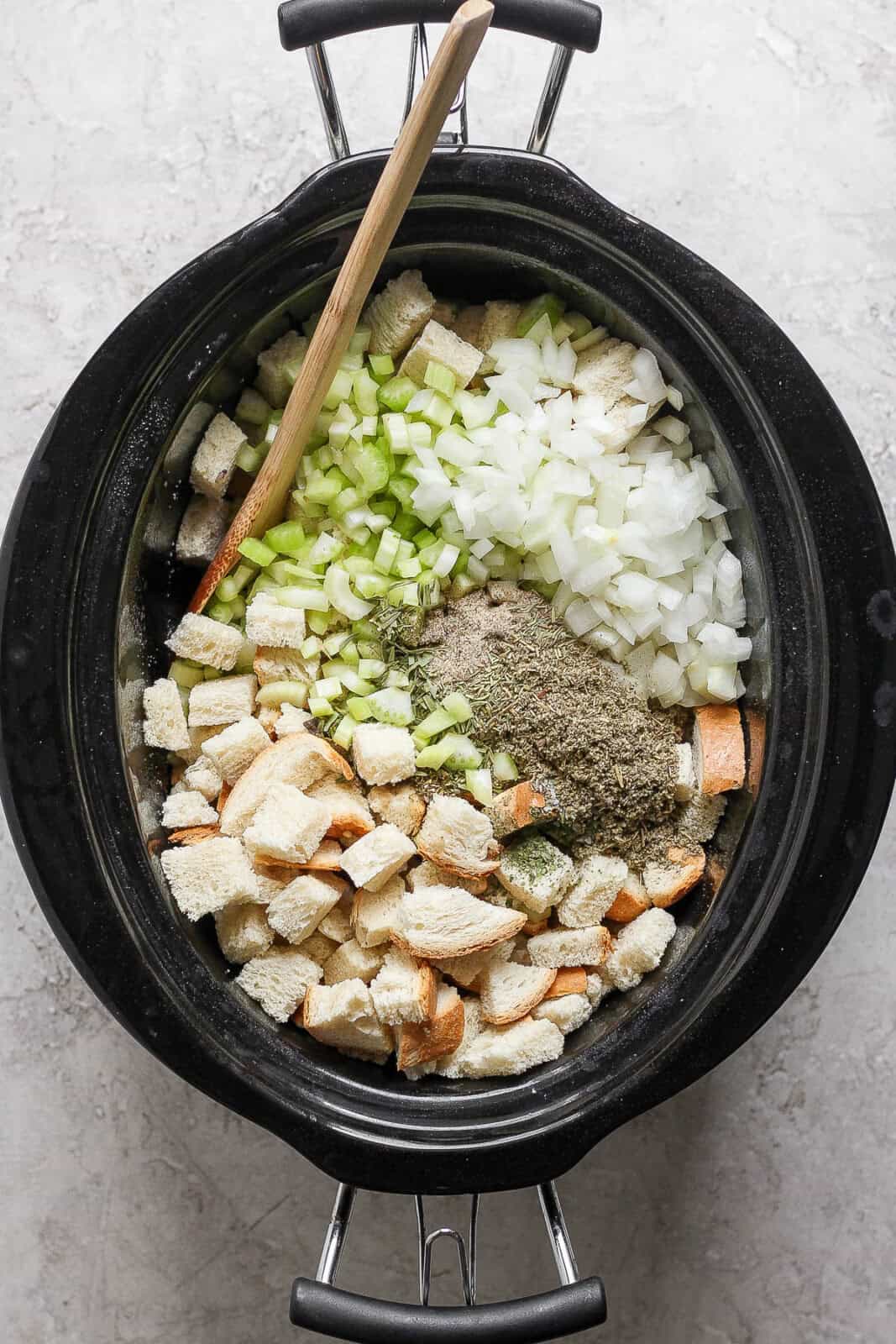 Celery, onion, seasonings, and bread cubes added to the crock pot.