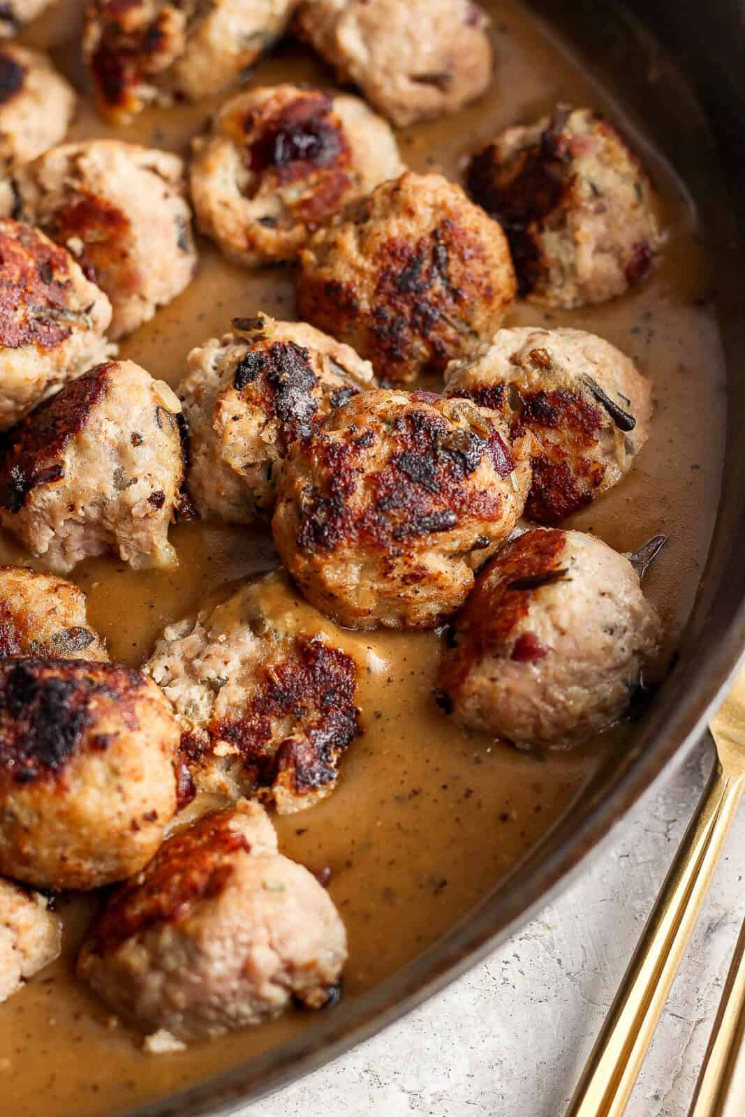 Seared Thanksgiving meatballs in a cast iron skillet with gravy.