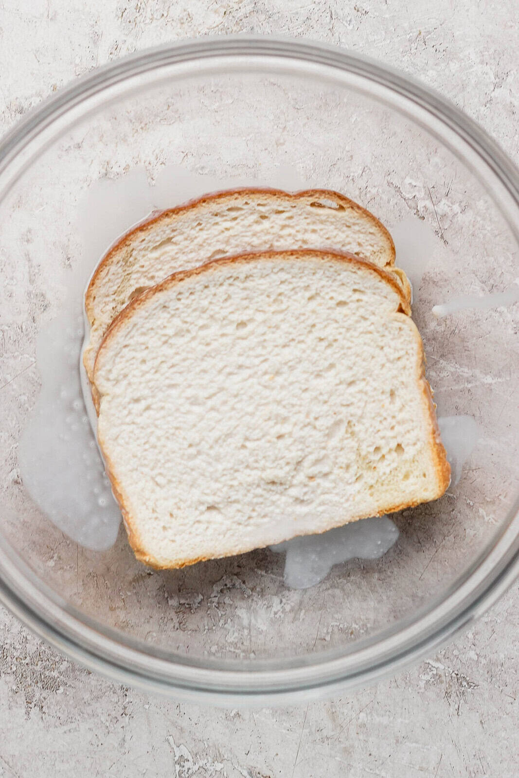 Two pieces of bread in a bowl topped with half and half.