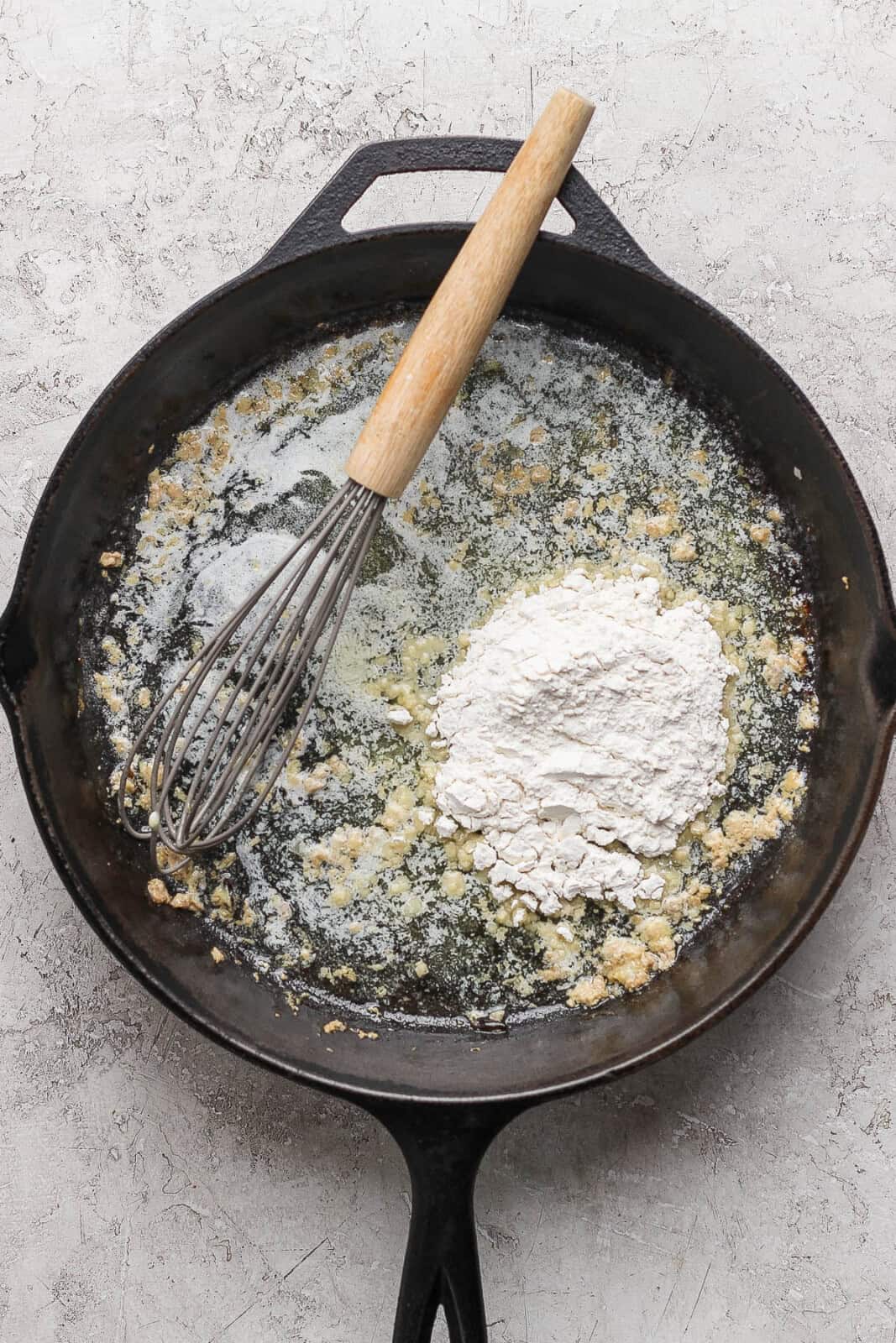 Butter melted in the cast iron skillet with flour and a whisk to make gravy for thanksgiving meatballs.