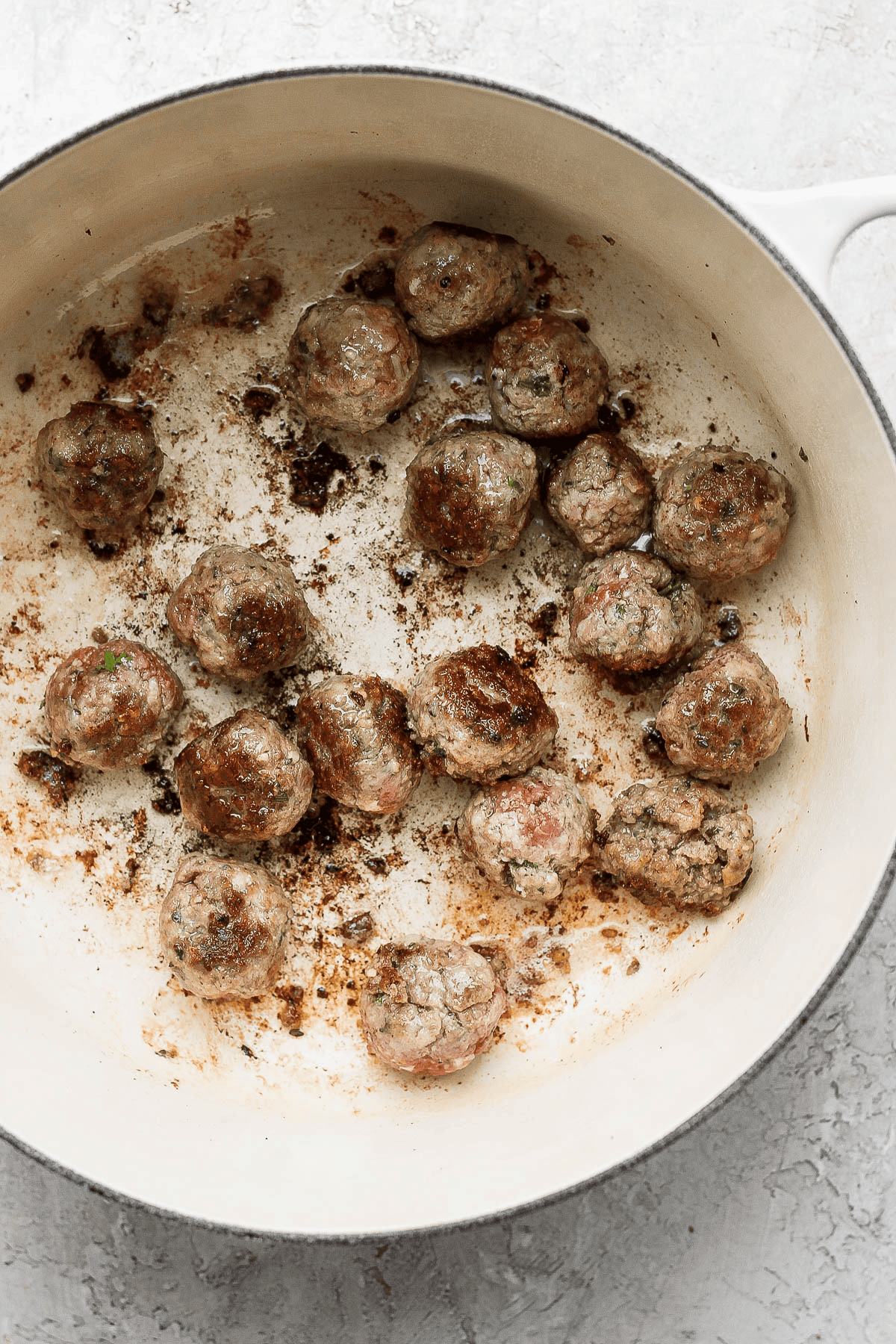 Meatballs for Italian wedding soup searing in a large dutch oven.